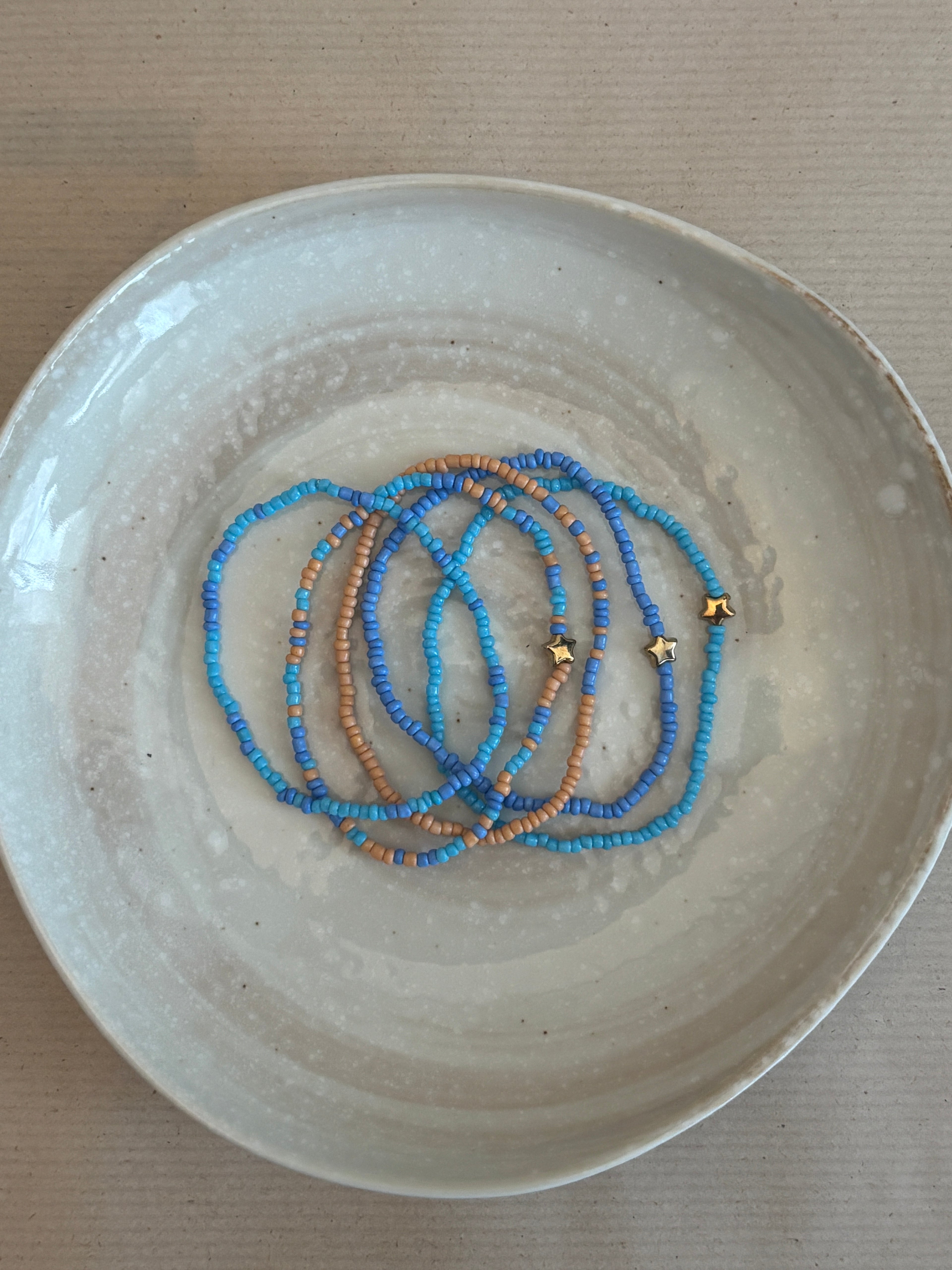 Beaded bracelet set on a textured ceramic plate 