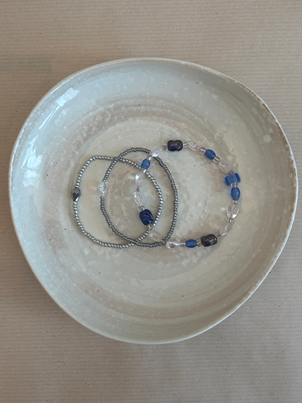 Bracelet with blue and clear beads on a beige plate