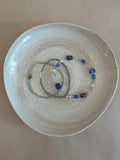 Bracelet with blue and clear beads on a beige plate