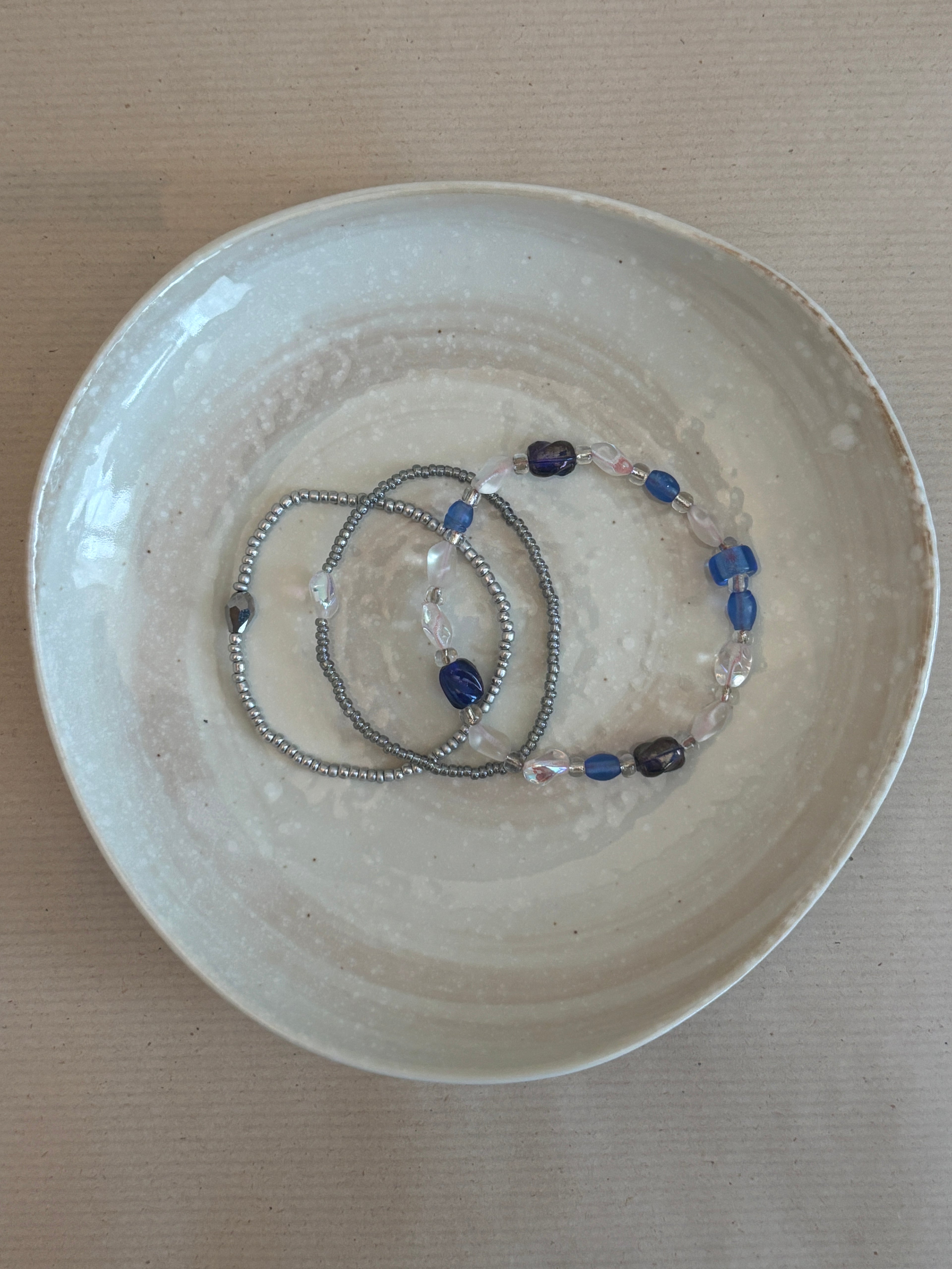 Bracelet with blue and clear beads on a beige plate
