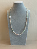 Pearl necklace on a gray jewelry display block against a beige background