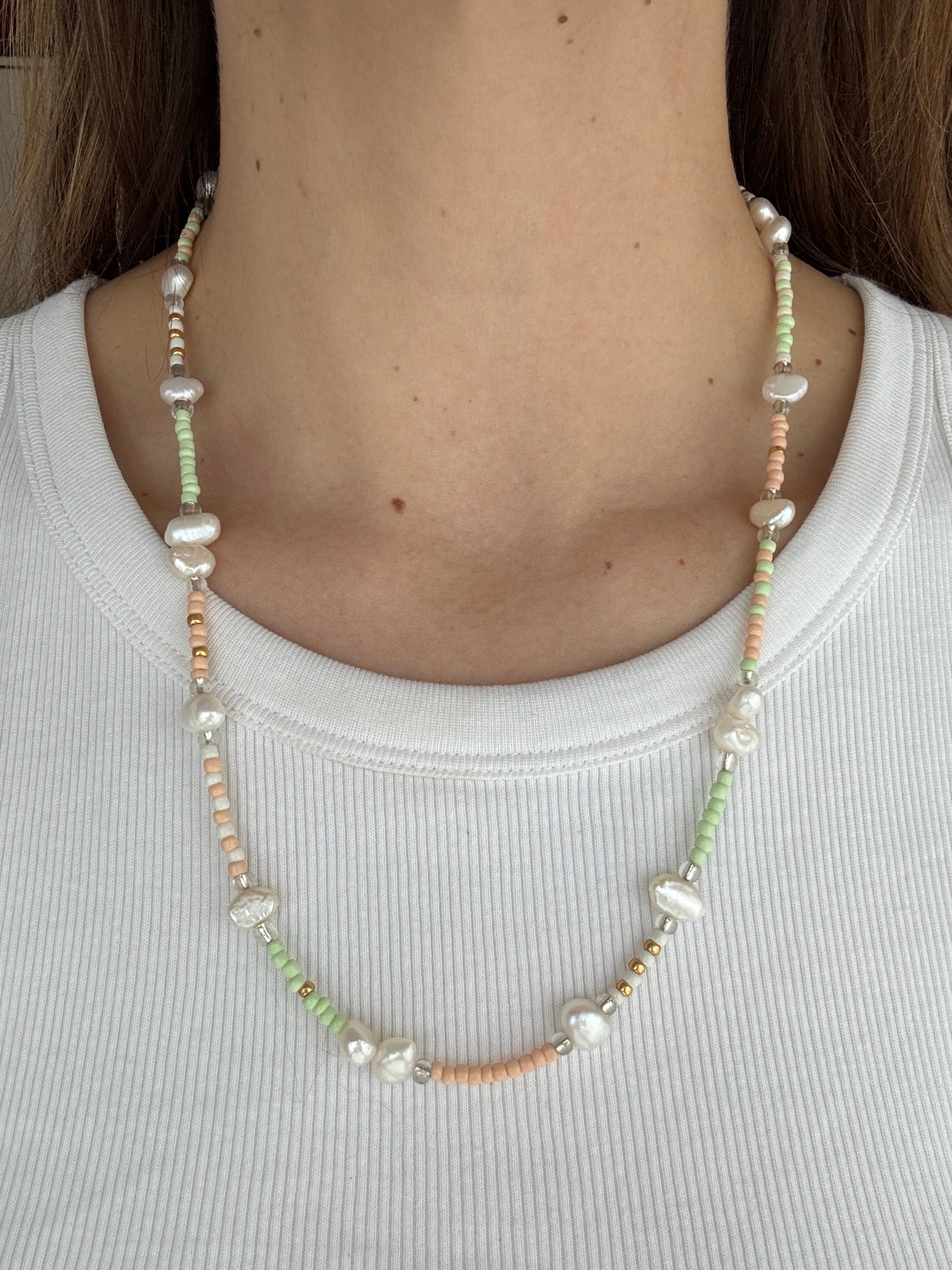 Close-up of a beaded necklace worn by a person on a plain background