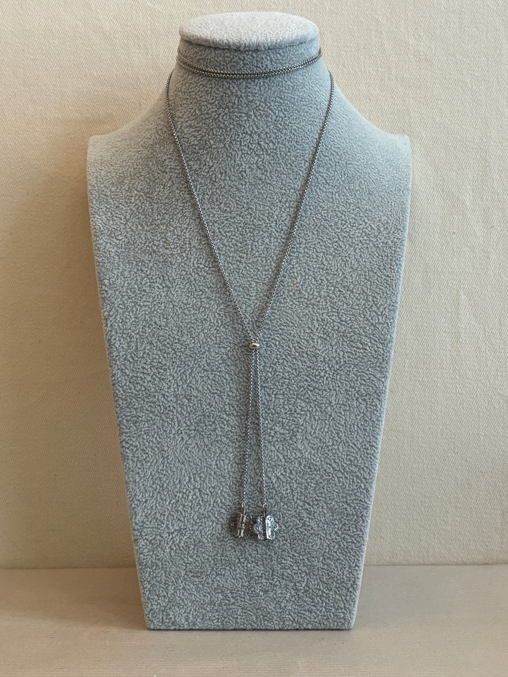 Mannequin wearing a light gray dress with a necklace on a beige background