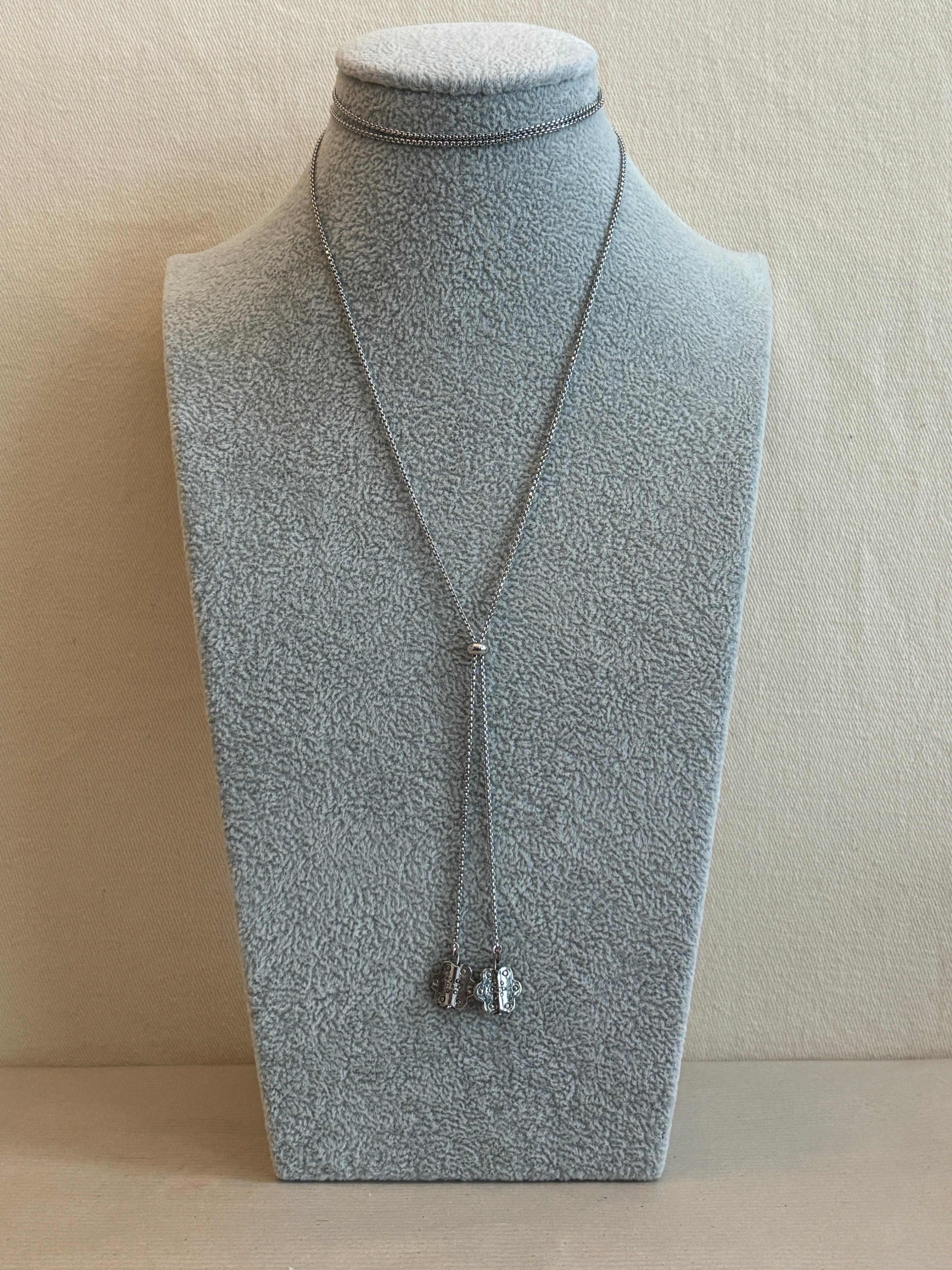 Mannequin wearing a light gray dress with a necklace on a beige background