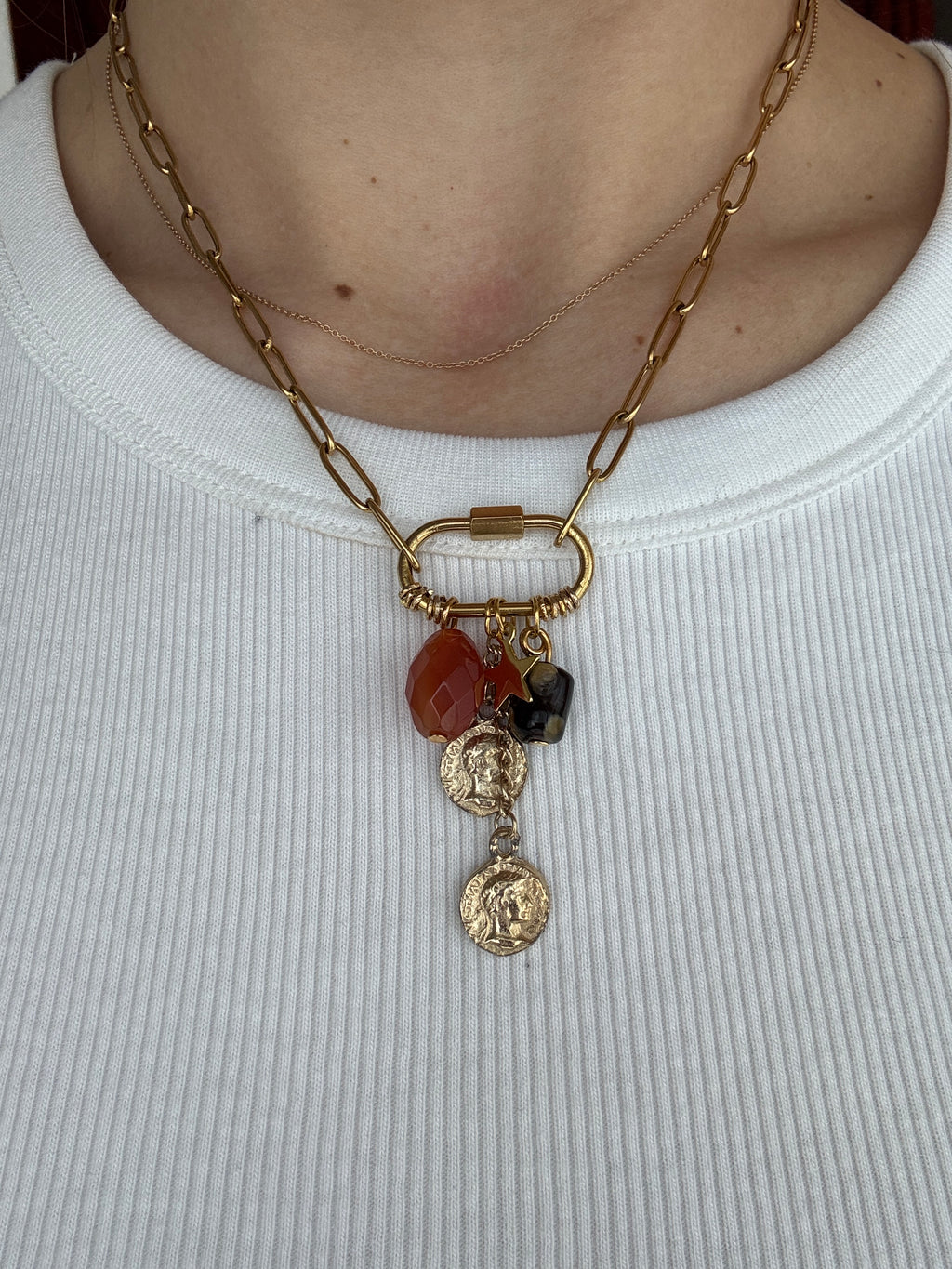 Gold chain necklace with charms on a white background