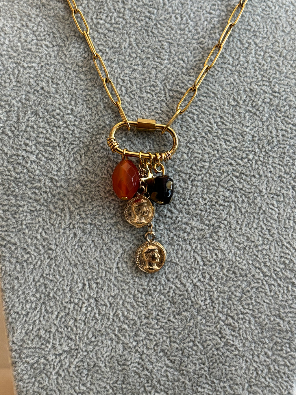 Necklace with gold chain and colorful beads on a textured gray surface