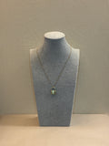 necklace on a mannequin bust against a beige Wall 