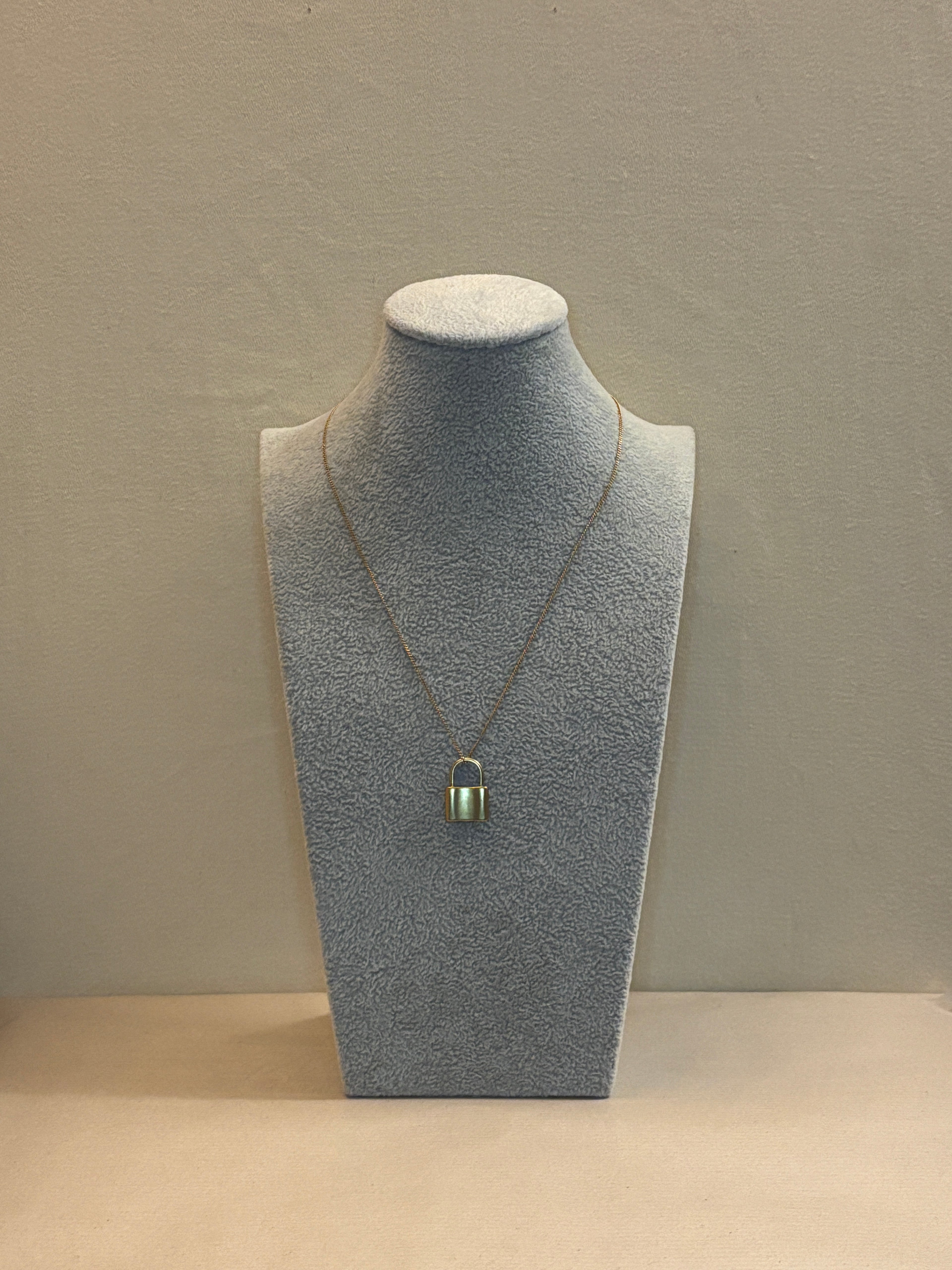 necklace on a mannequin bust against a beige Wall 