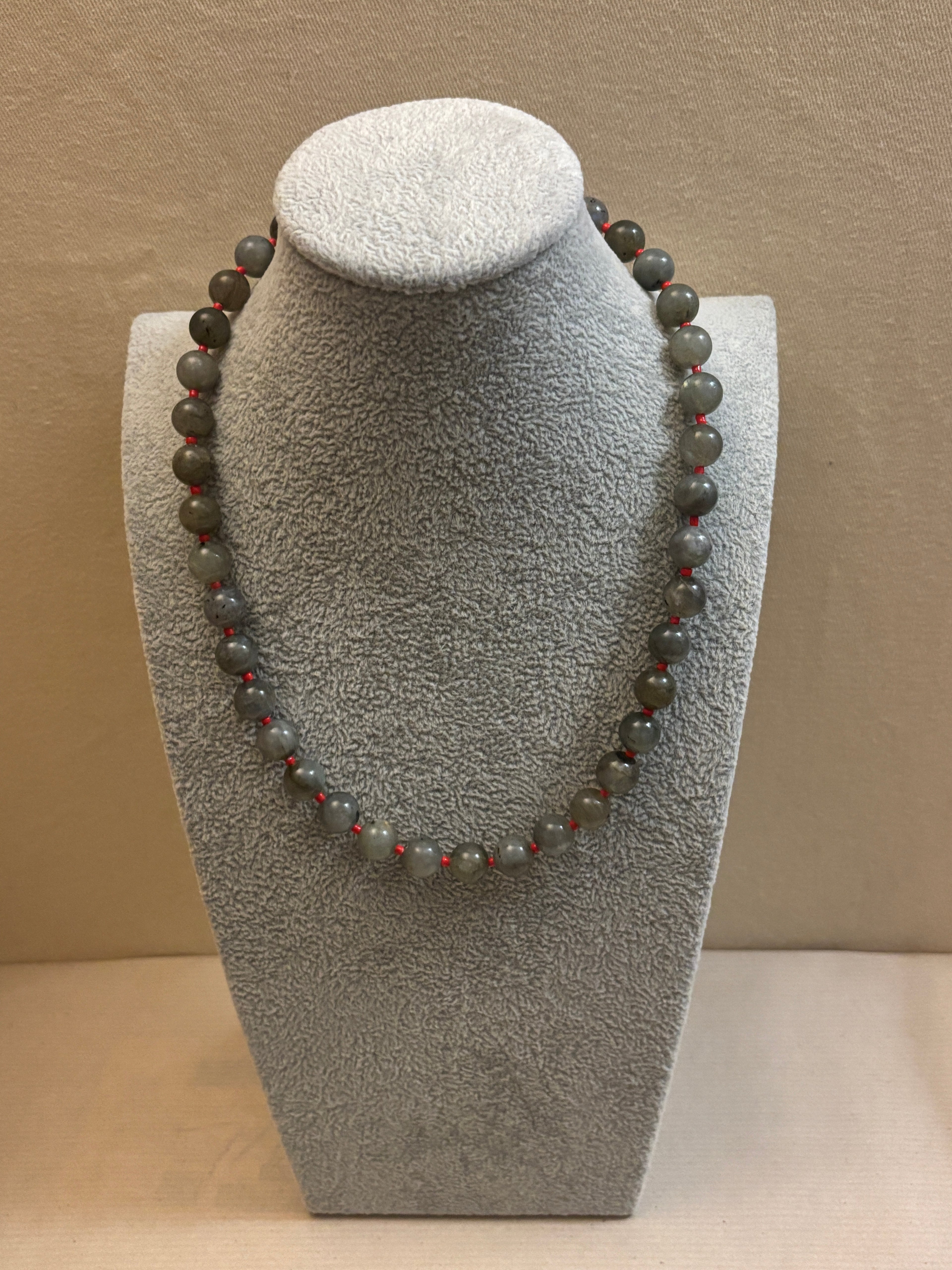 Beaded necklace on a gray stone stand against a beige background