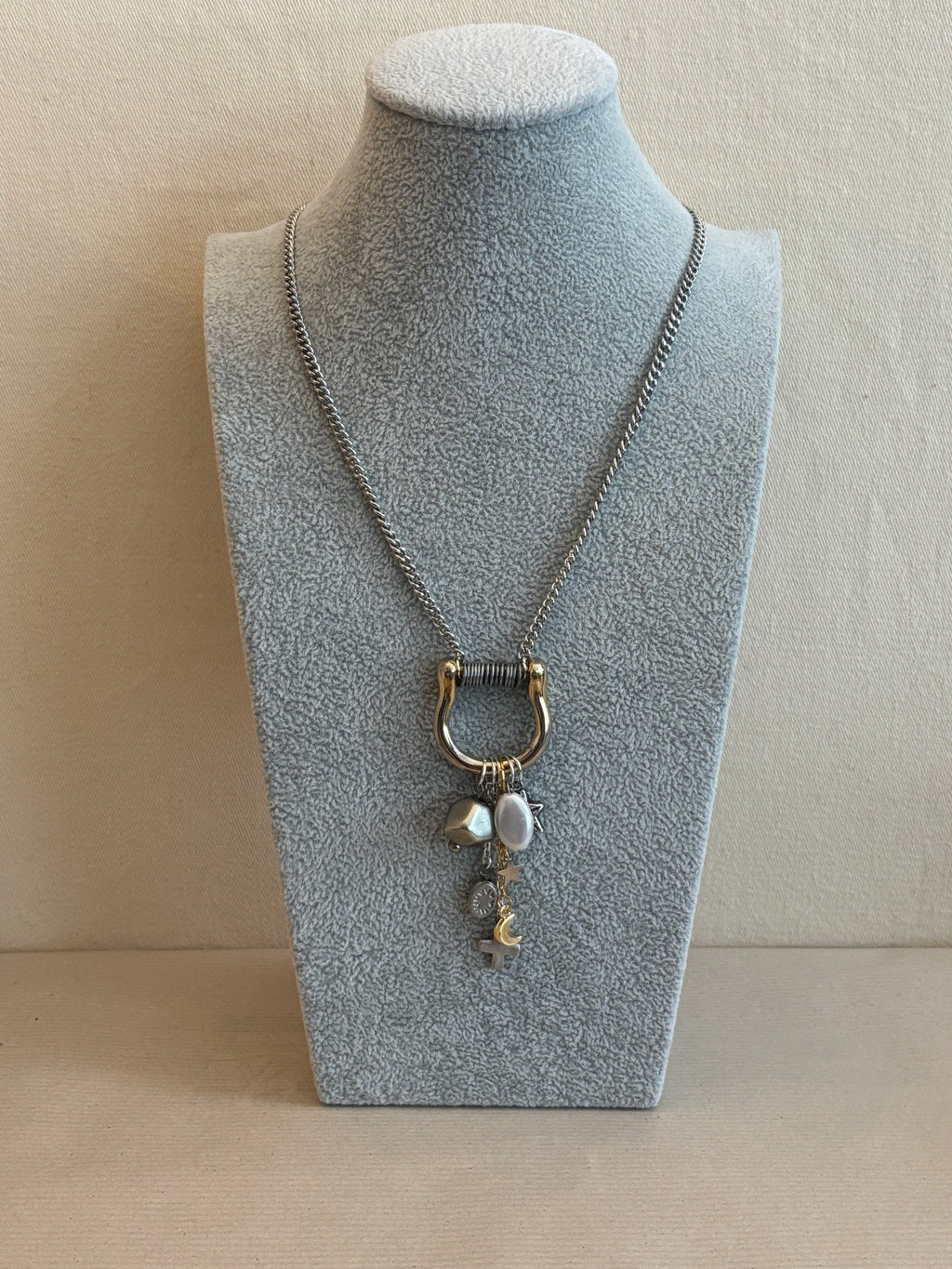 Necklace with a pendant on a gray stand against a beige background