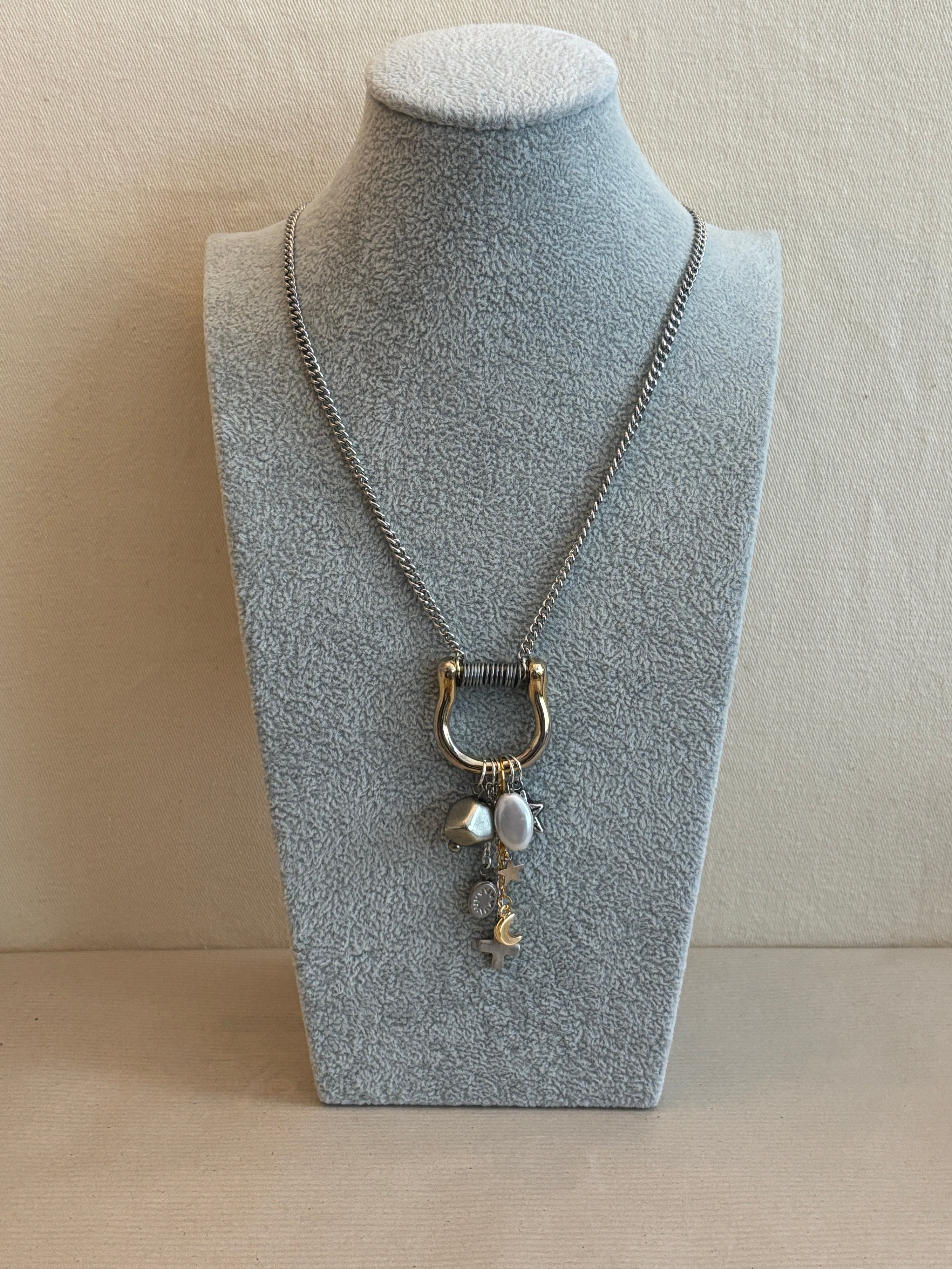 Necklace with a pendant on a gray stand against a beige background