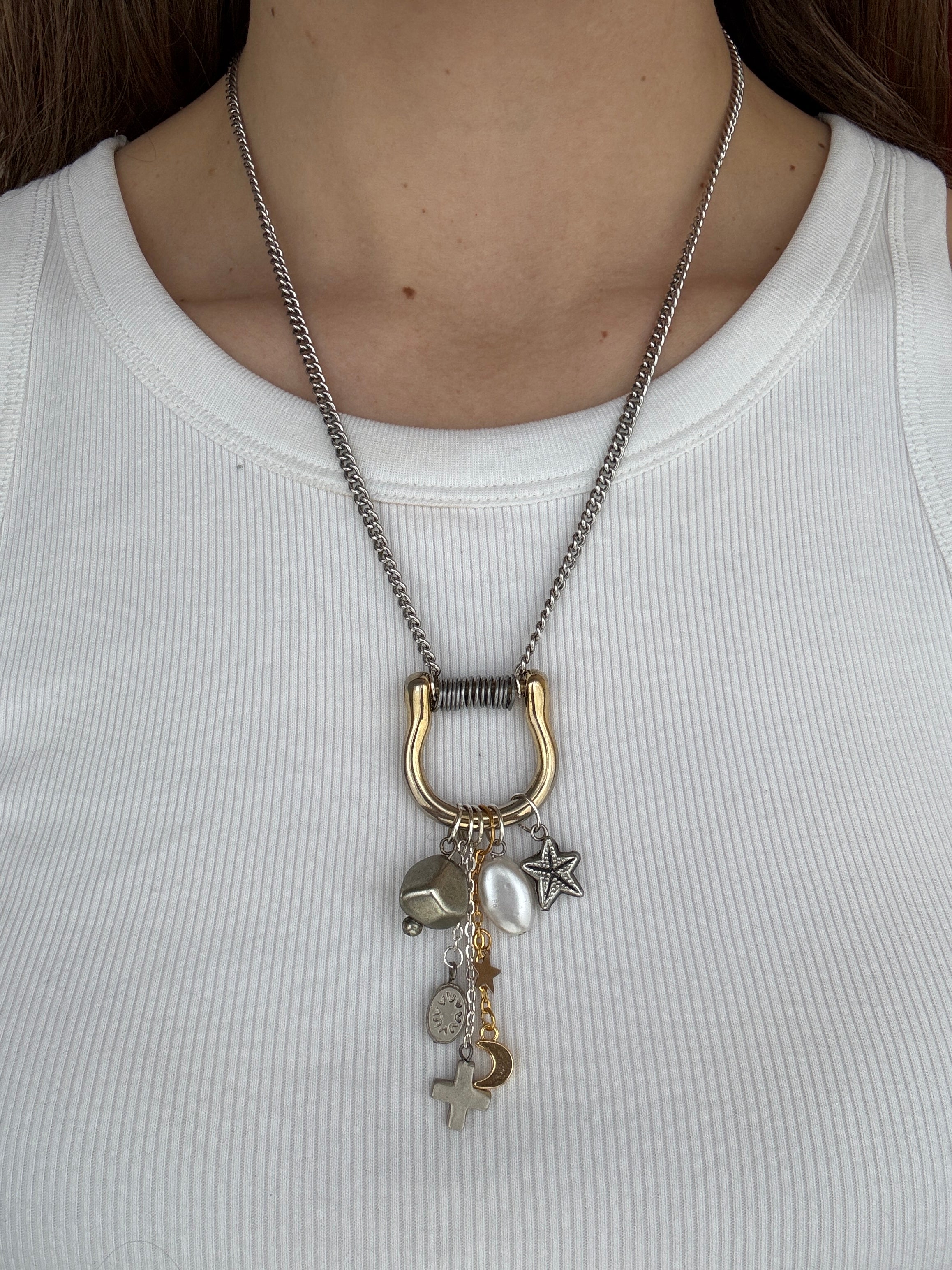 Necklace with charms worn by a person on a plain background