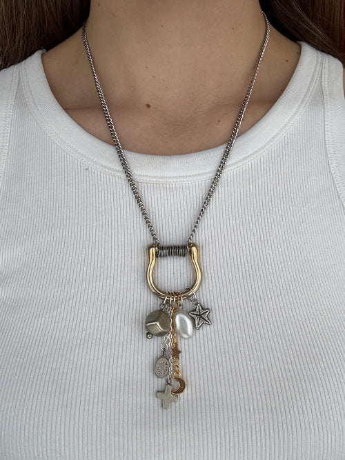 Necklace with charms worn by a person on a plain background