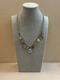 Necklace with various charms on a gray bust against a beige background