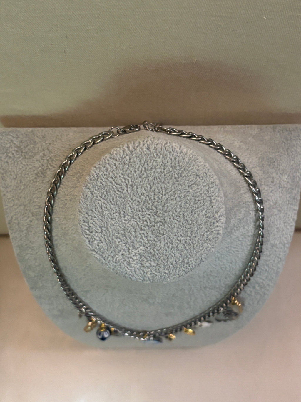 Silver chain necklace on a textured gray stand