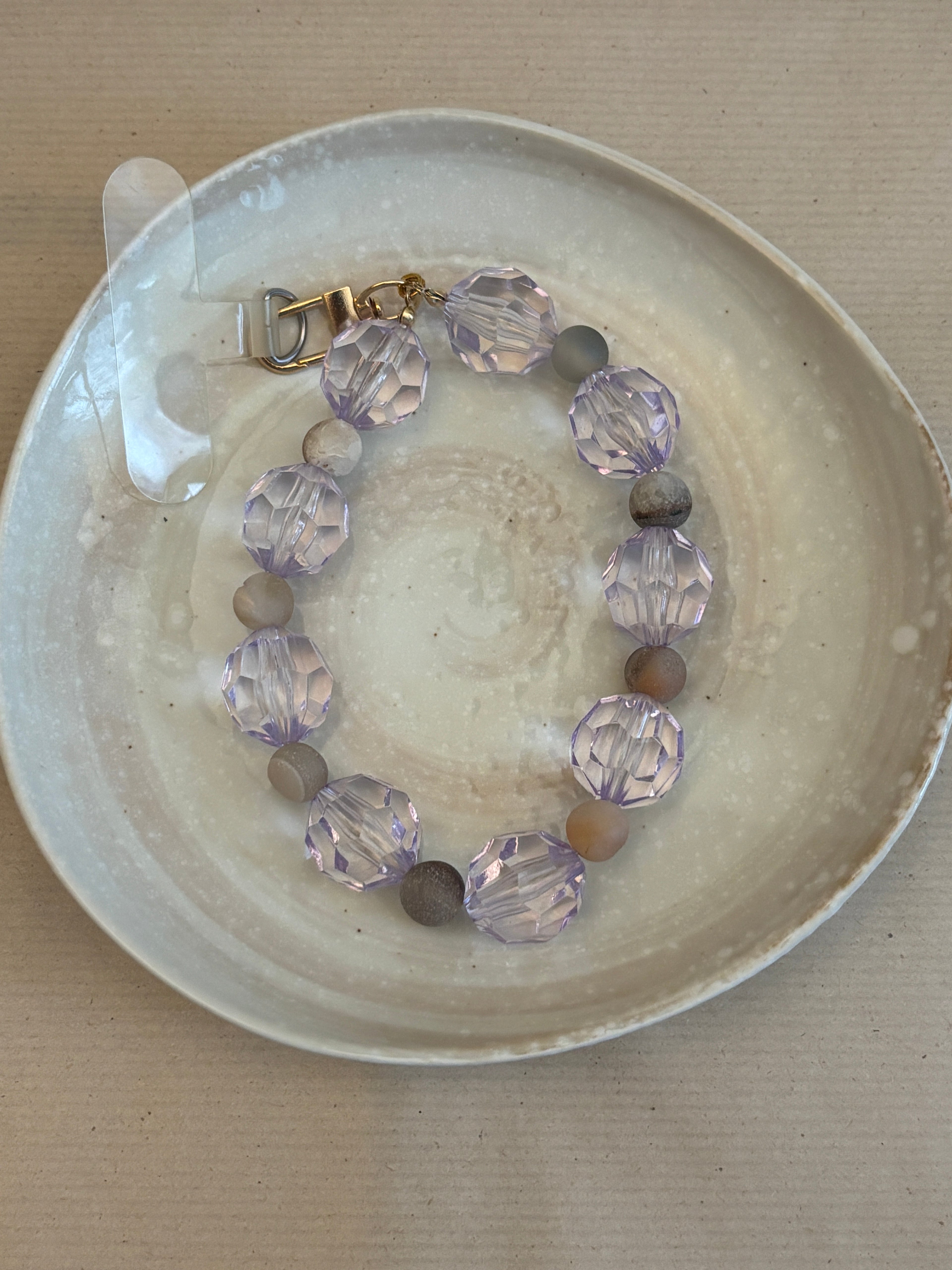 Phone bracelet with purple and brown beads on a ceramic plate