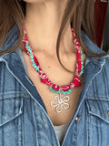 Person wearing a red and turquoise beaded necklace with a floral design.