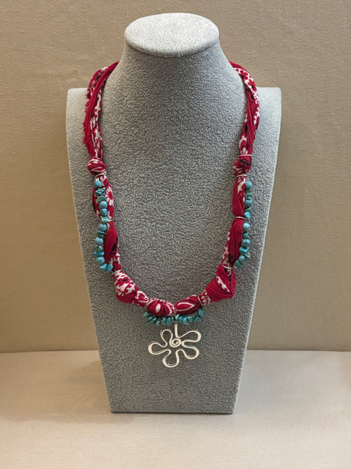 Decorative necklace with floral design on a gray stand against a beige background
