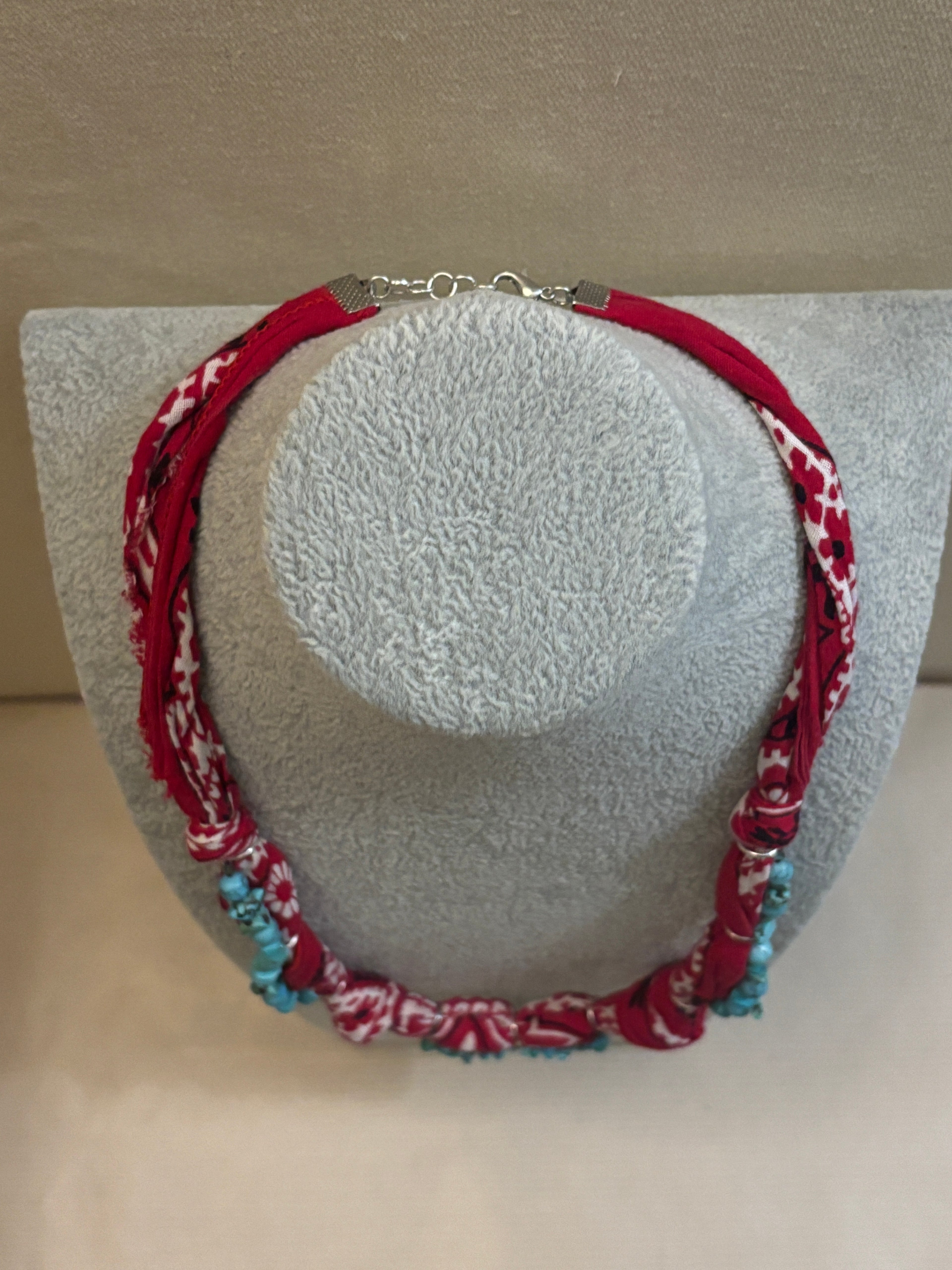 Red and white patterned necklace on a gray stand