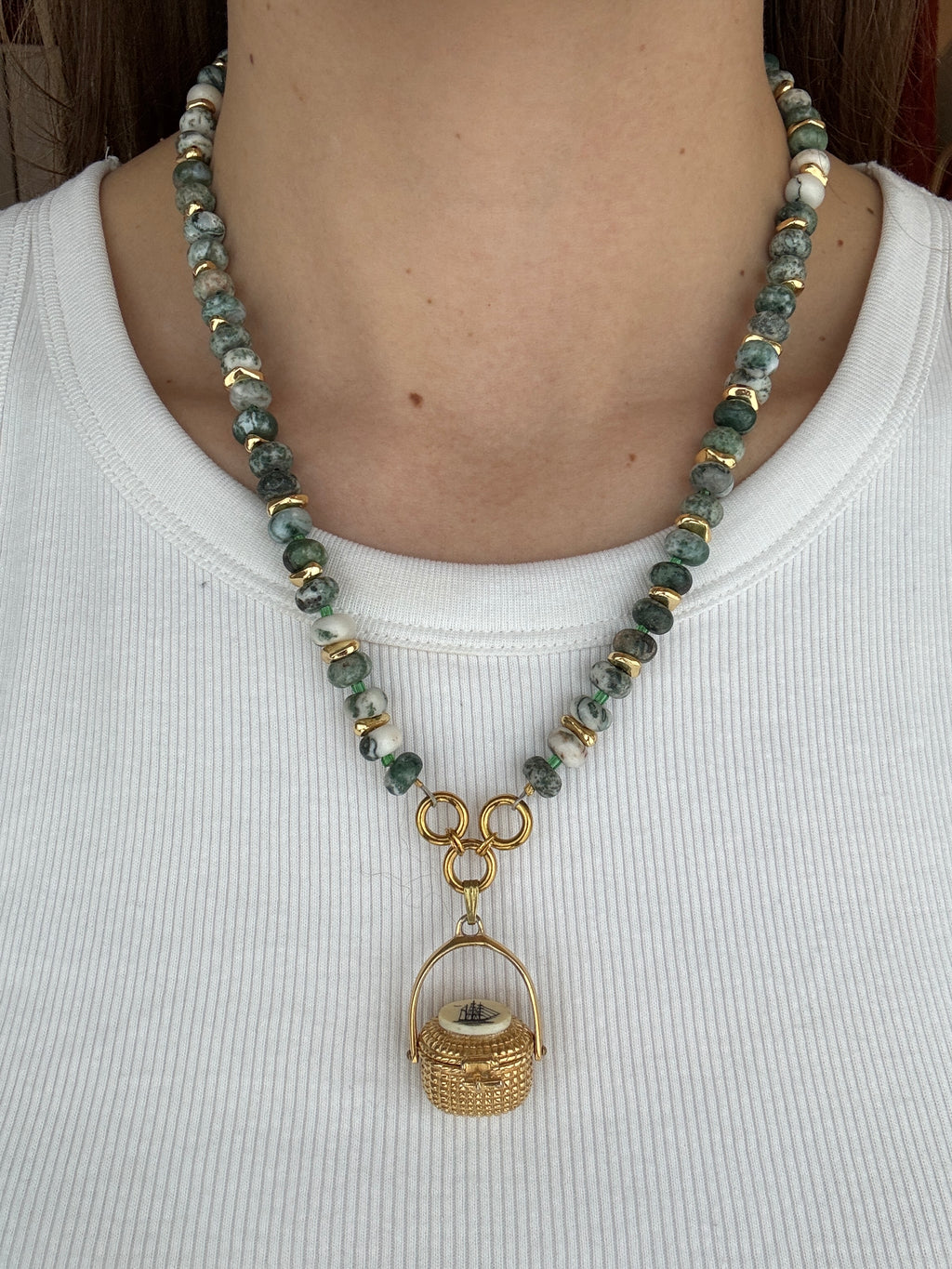 Necklace with green beads and gold accents on a white background