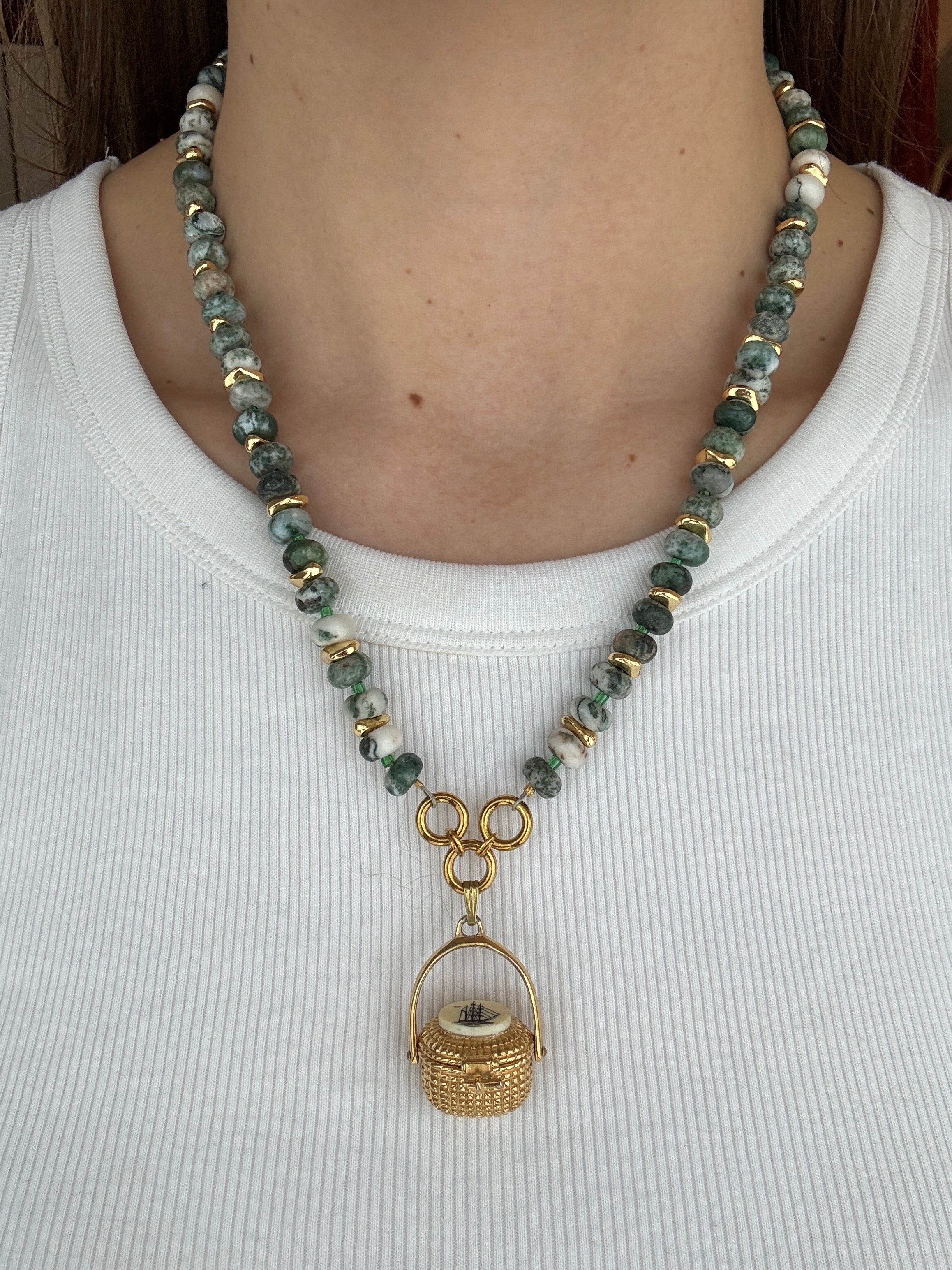 Necklace with green beads and gold accents on a white background