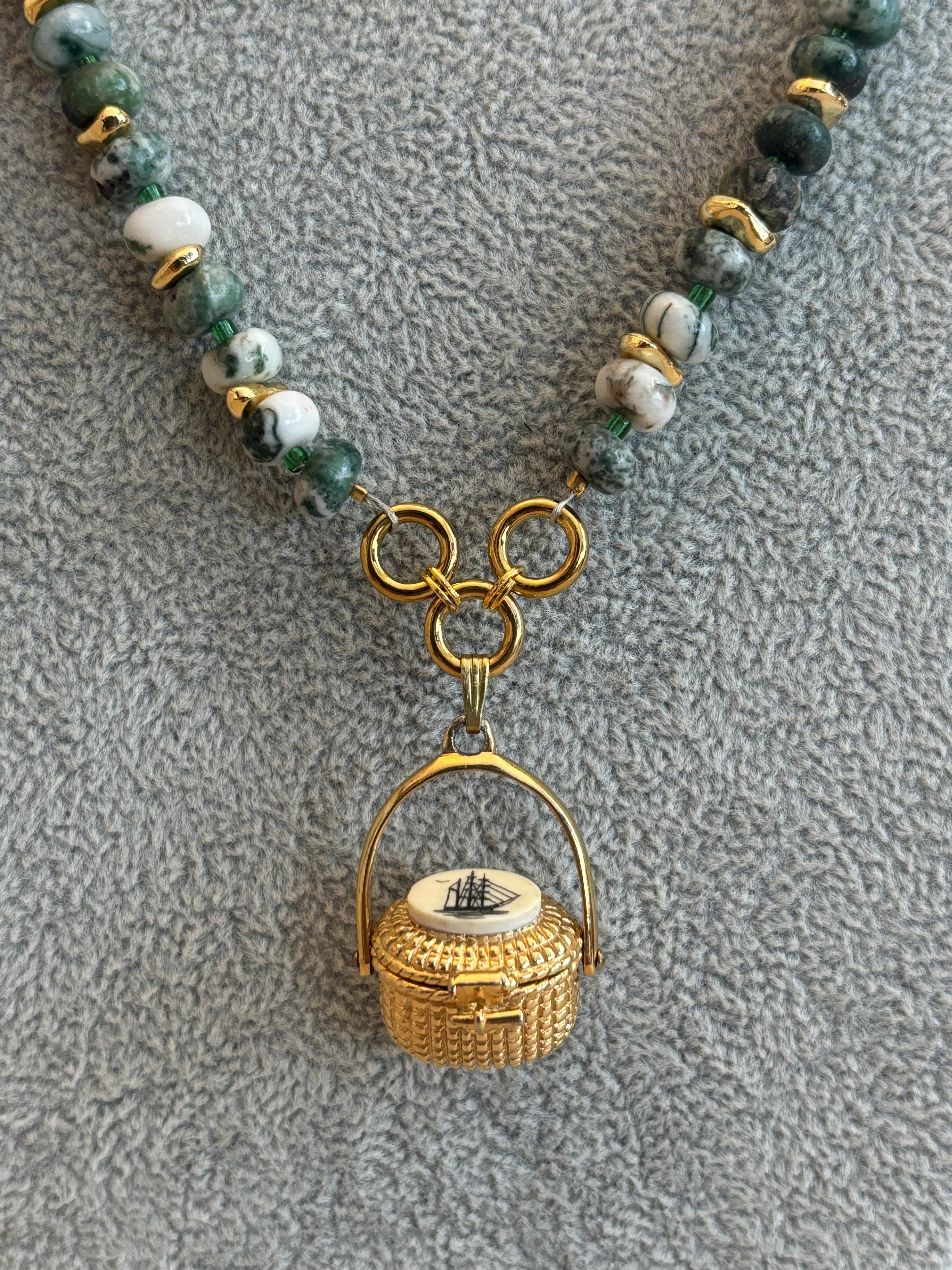 Necklace with green beads and gold clasp on a textured gray background