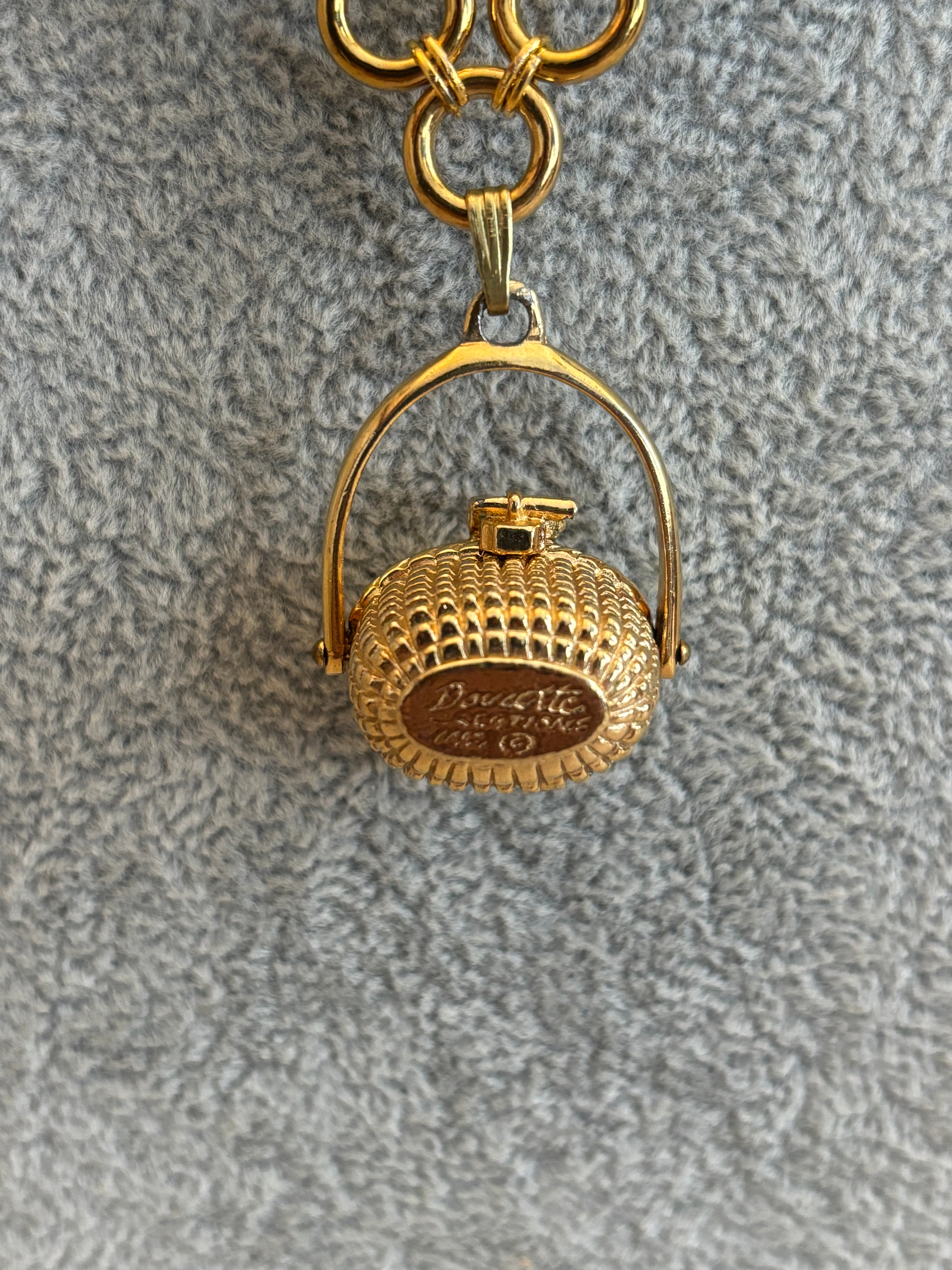 Gold thimble keychain on a textured gray background
