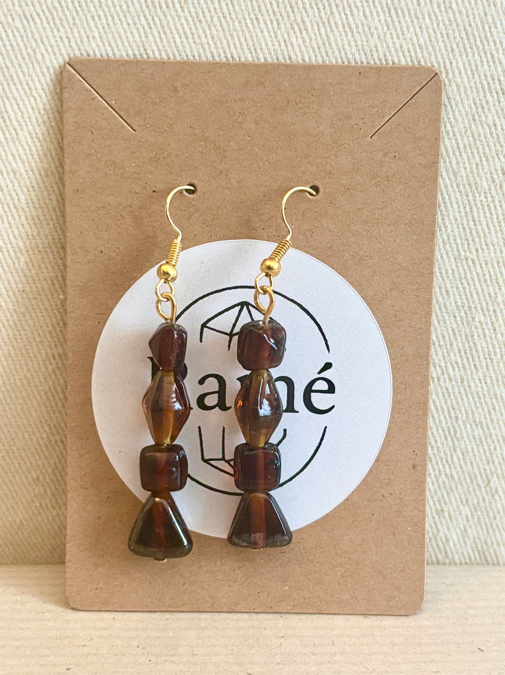 Brown beaded earrings on a cardboard card with a Ramé branded logo.