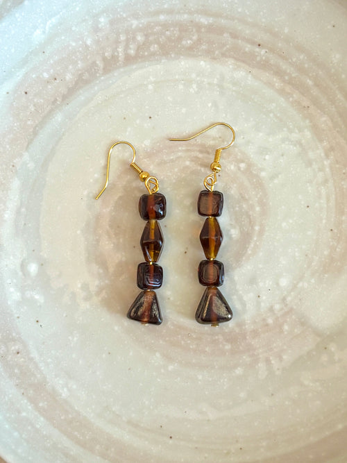 Pair of brown beaded earrings on a textured white surface