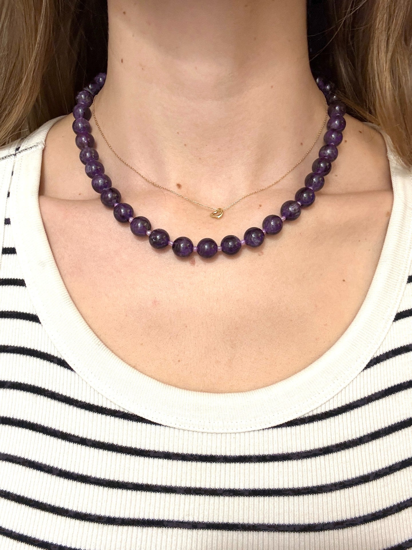 Purple beaded necklace worn by a person with a striped shirt