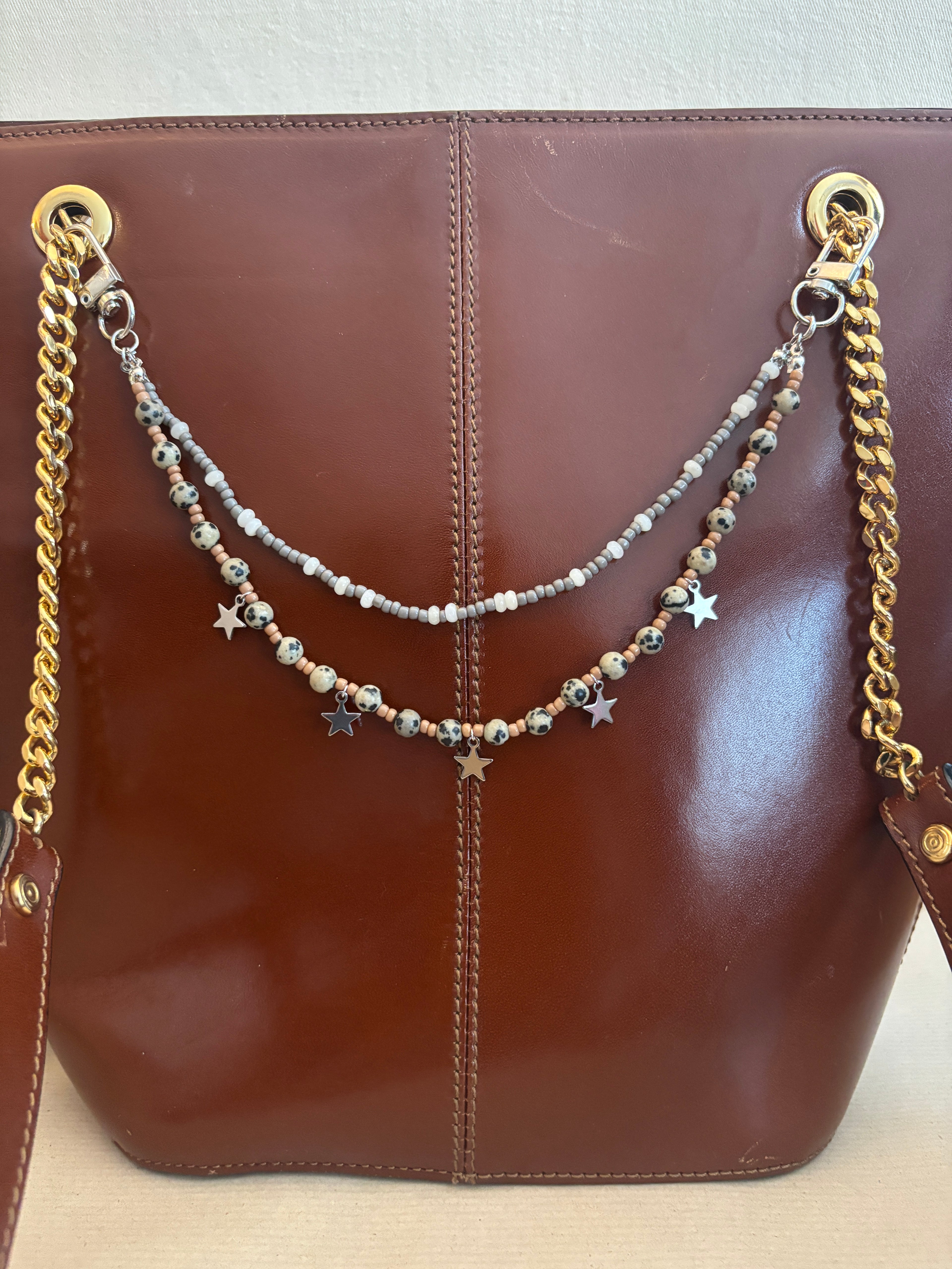 Necklace with star and chain details on a brown leather surface