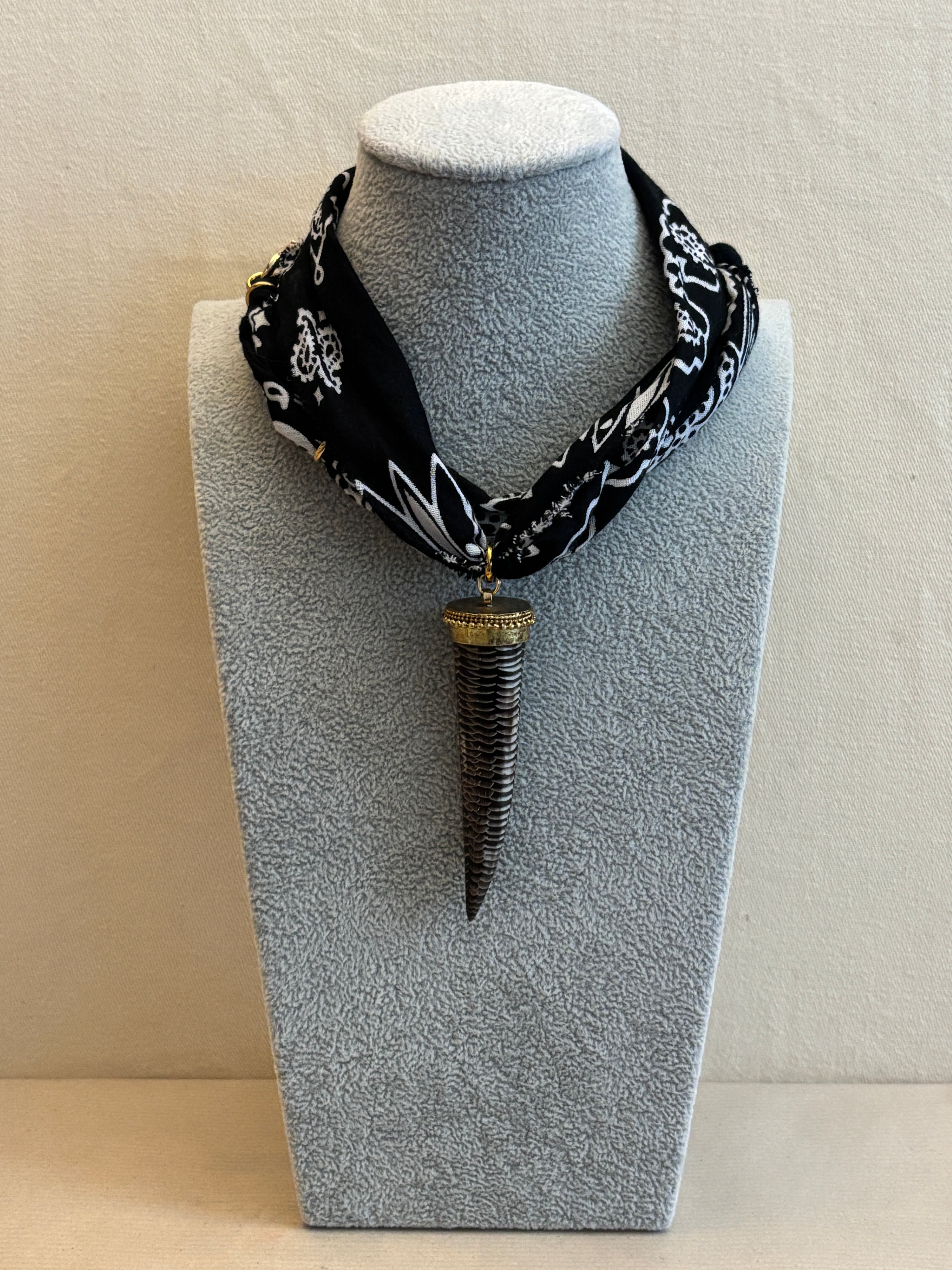 Black patterned headband on a gray stand against a beige wall