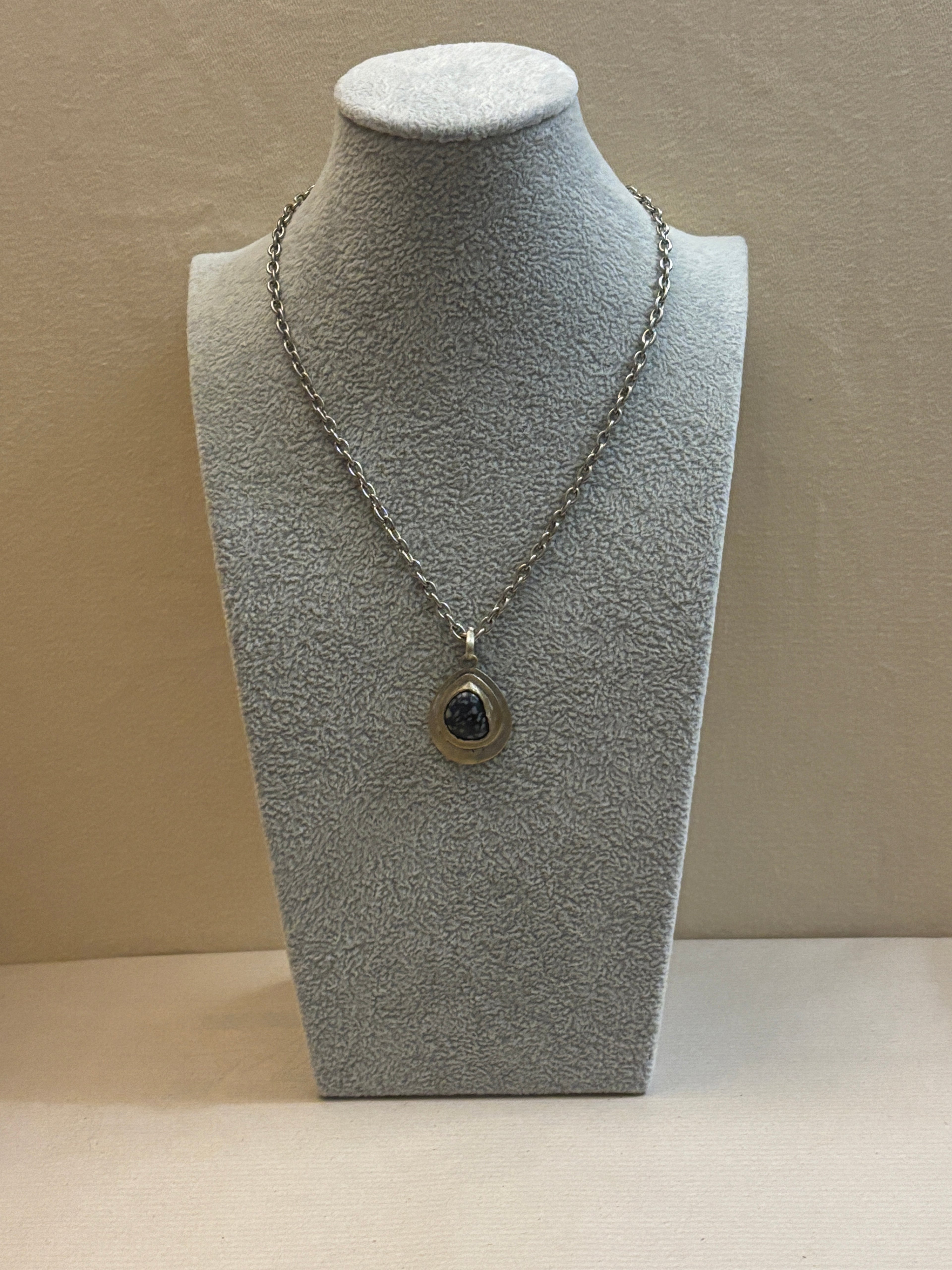 Necklace on a gray mannequin bust against a beige background