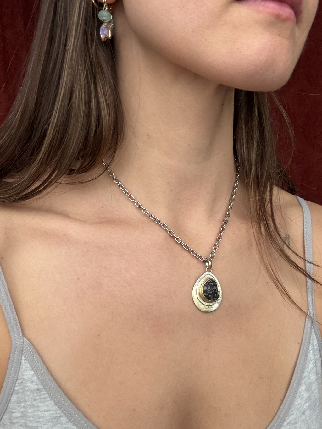 Necklace with a pendant worn by a person against a neutral background