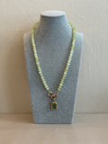 Necklace with a green gemstone pendant on a gray stand
