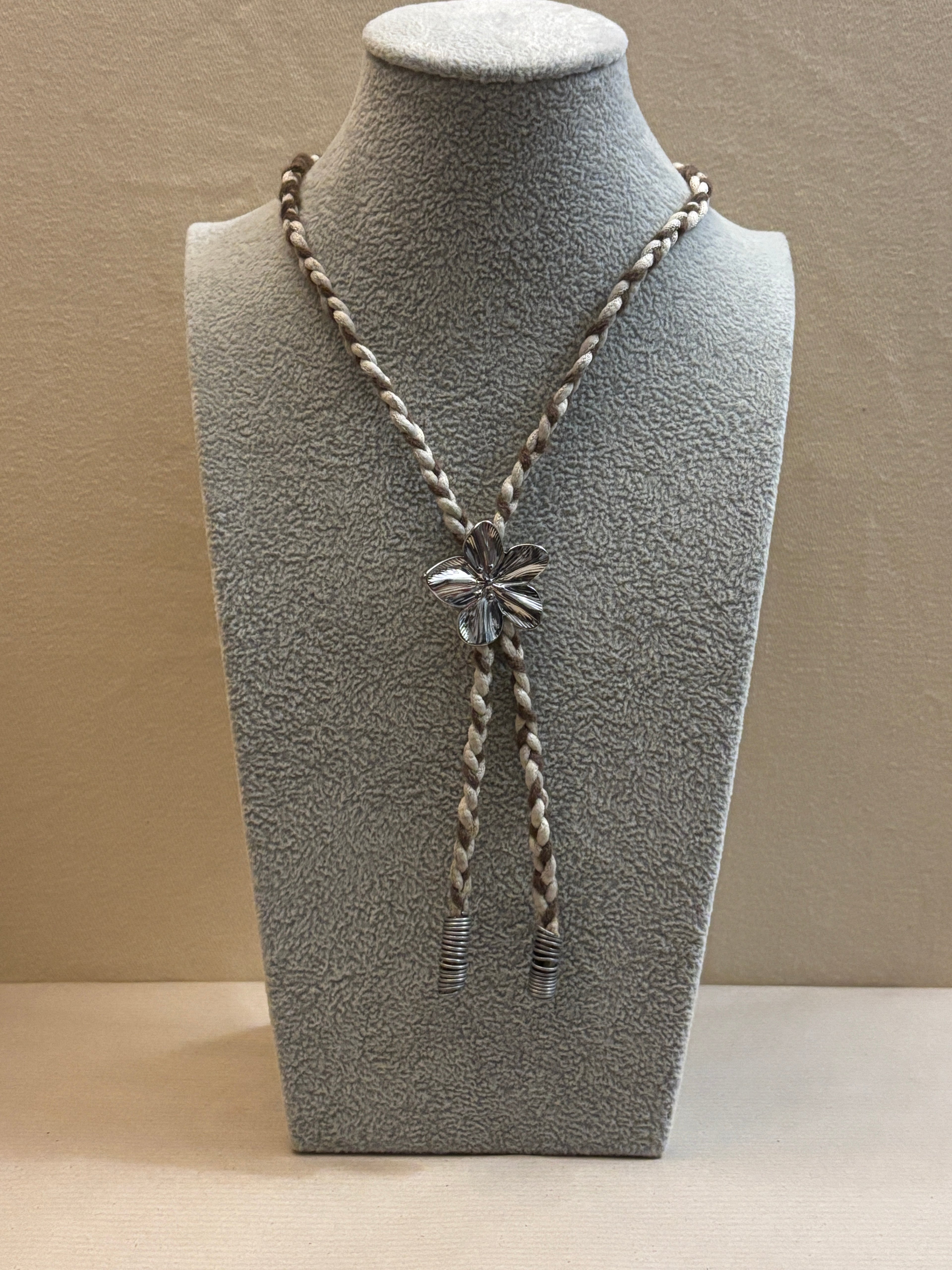 Necklace on a gray mannequin bust against a beige background