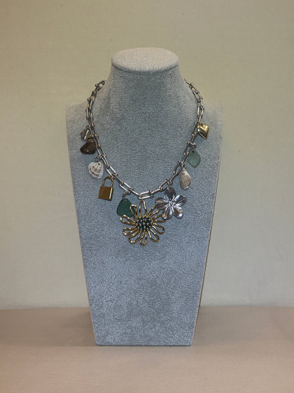 Silver necklace with charms on a silver chain against a beige background
