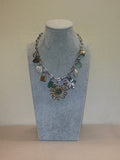 Silver necklace with charms on a silver chain against a beige background