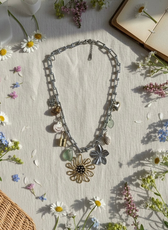 Necklace with floral pendants on a light surface with flowers