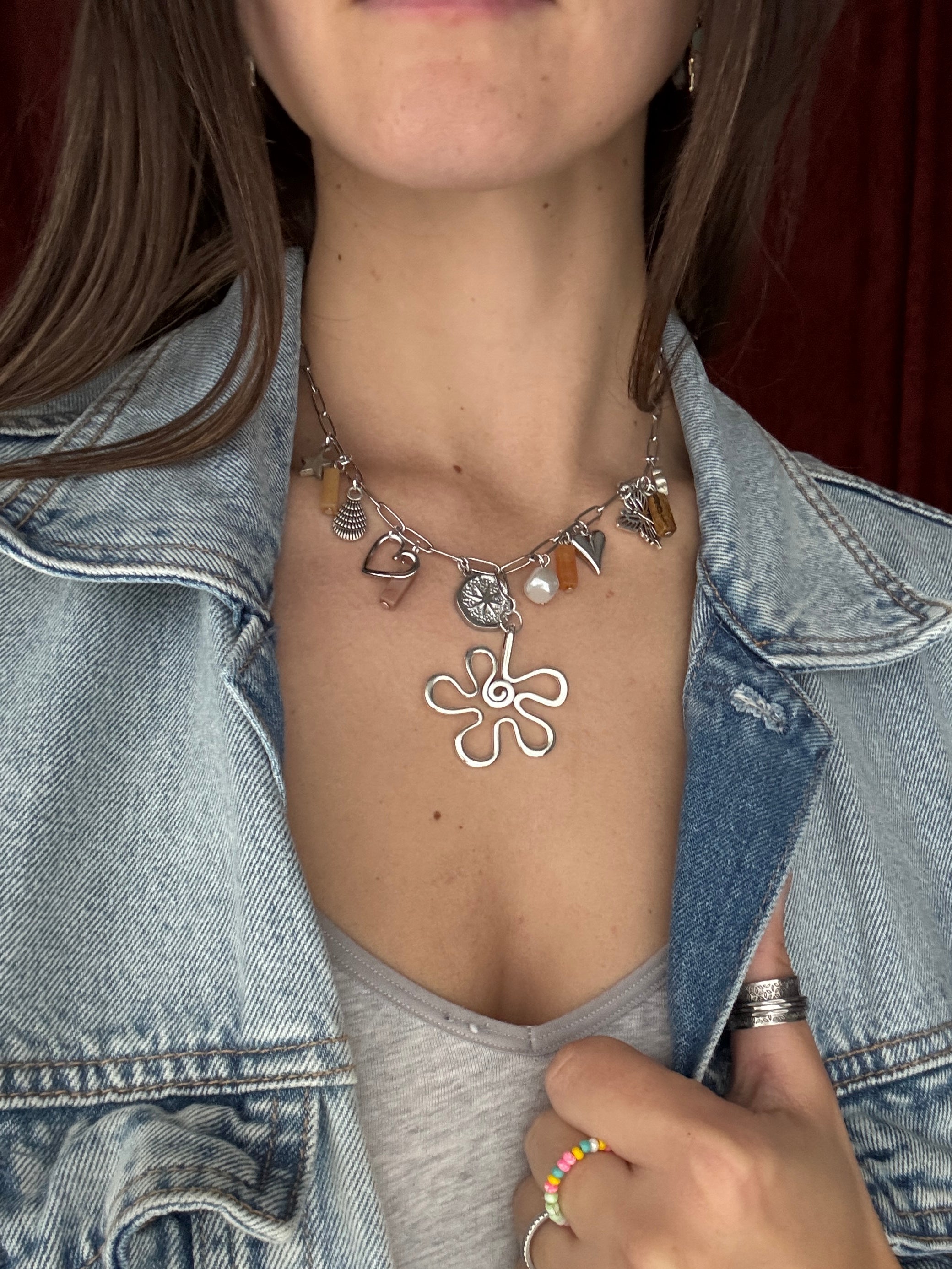 Person wearing a silver necklace with a floral design.