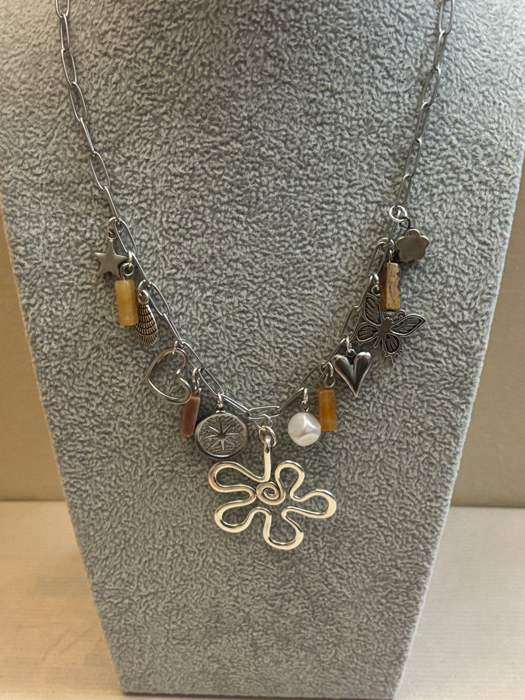 Silver necklace with various charms on a textured surface