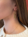Gold hoop earrings worn by a person with a neutral background