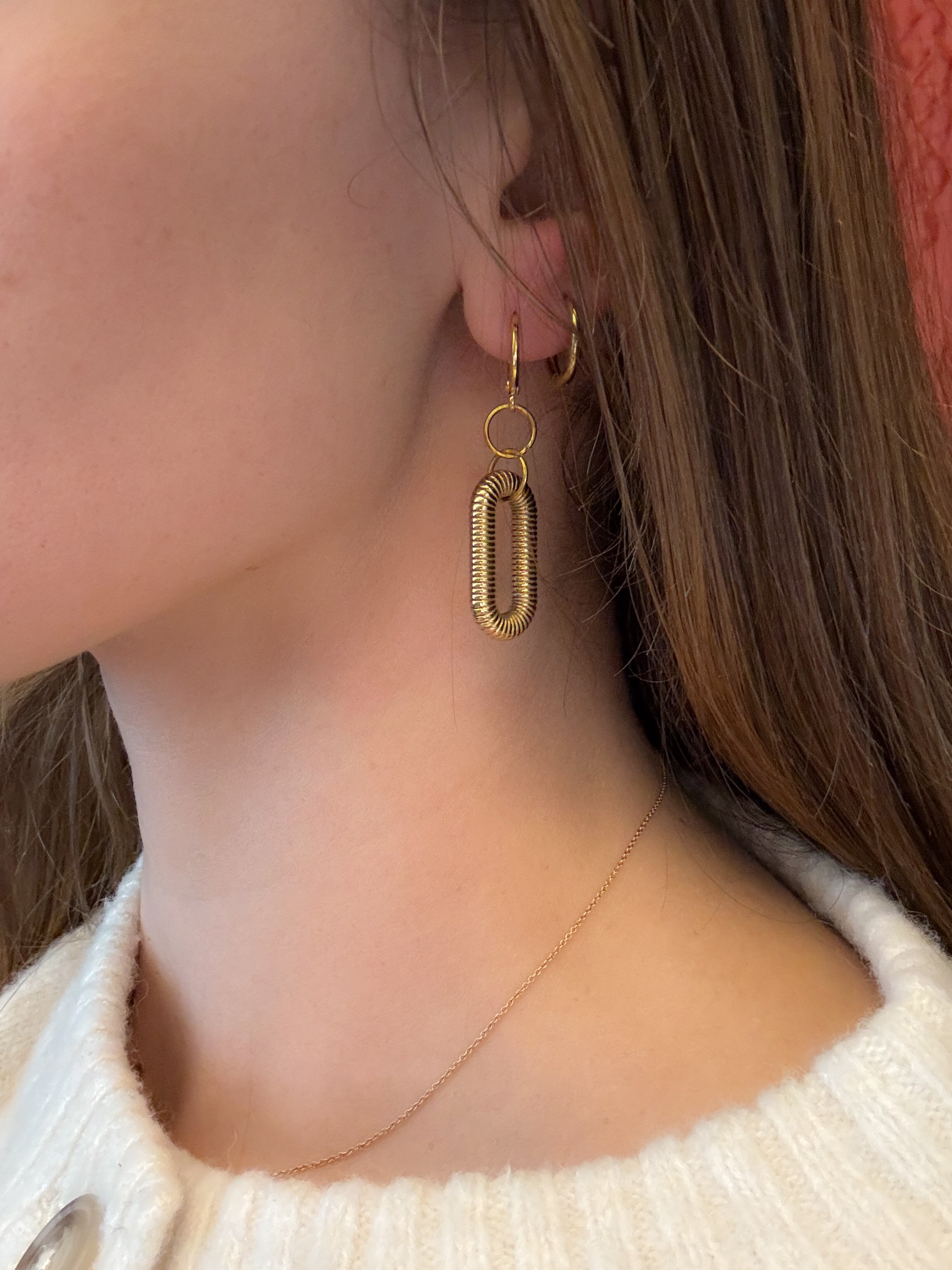 Gold hoop earrings worn by a person with a neutral background