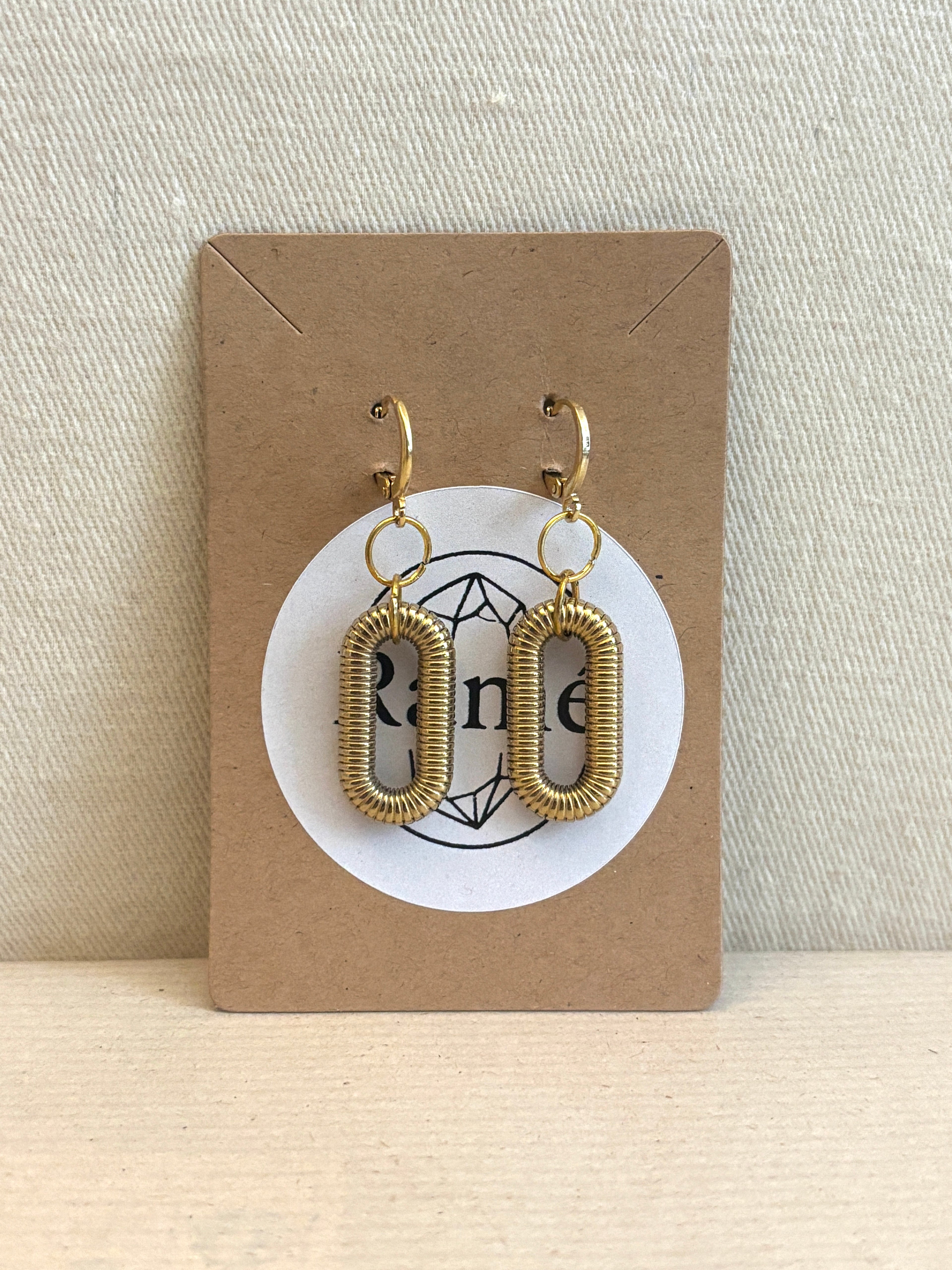 Gold hoop earrings on a cardboard card with a Ramé brand logo against a neutral background