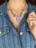 Person wearing a denim jacket with a colorful charm necklace