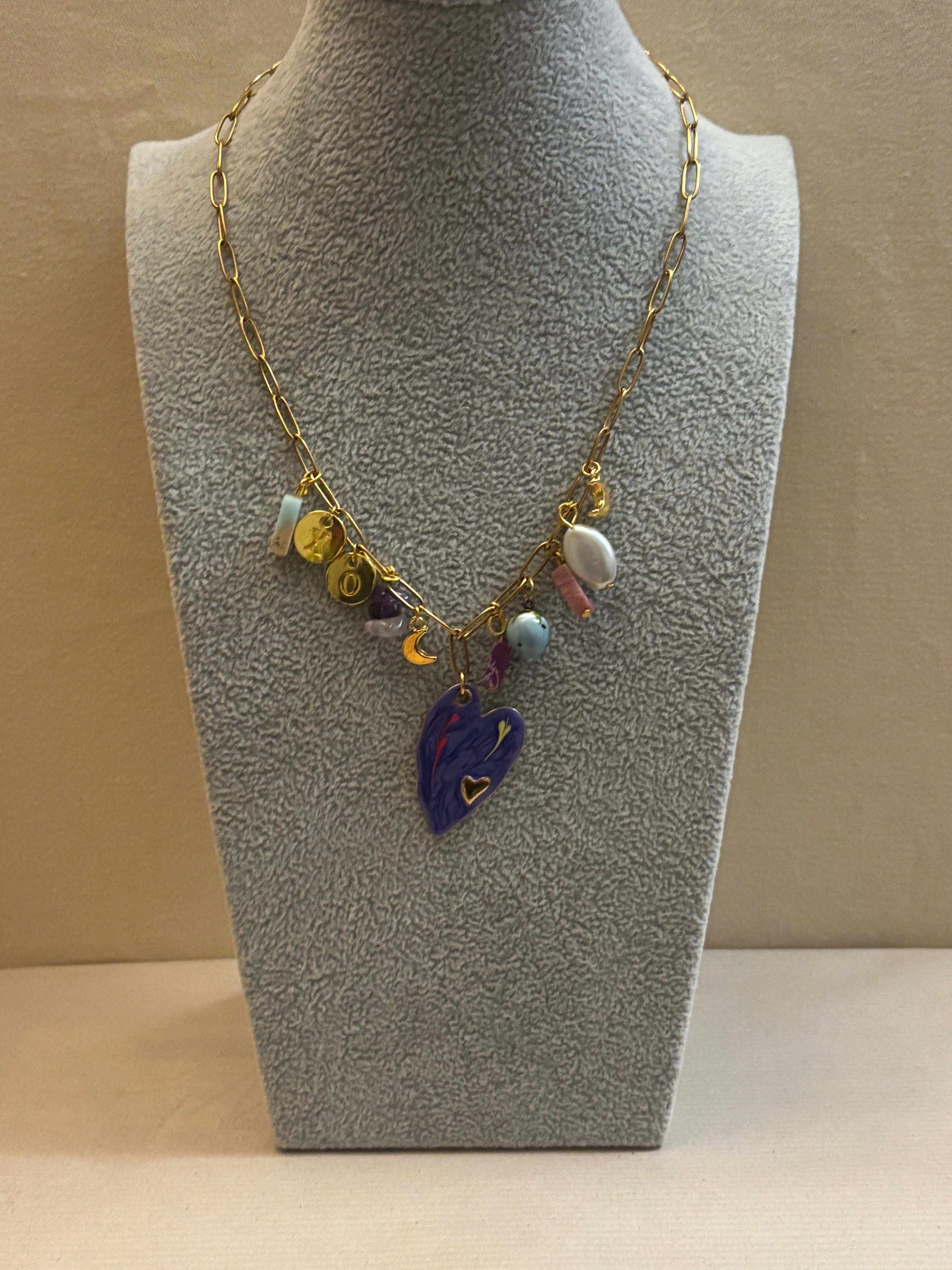 Necklace with colorful charms on a mannequin bust against a beige background