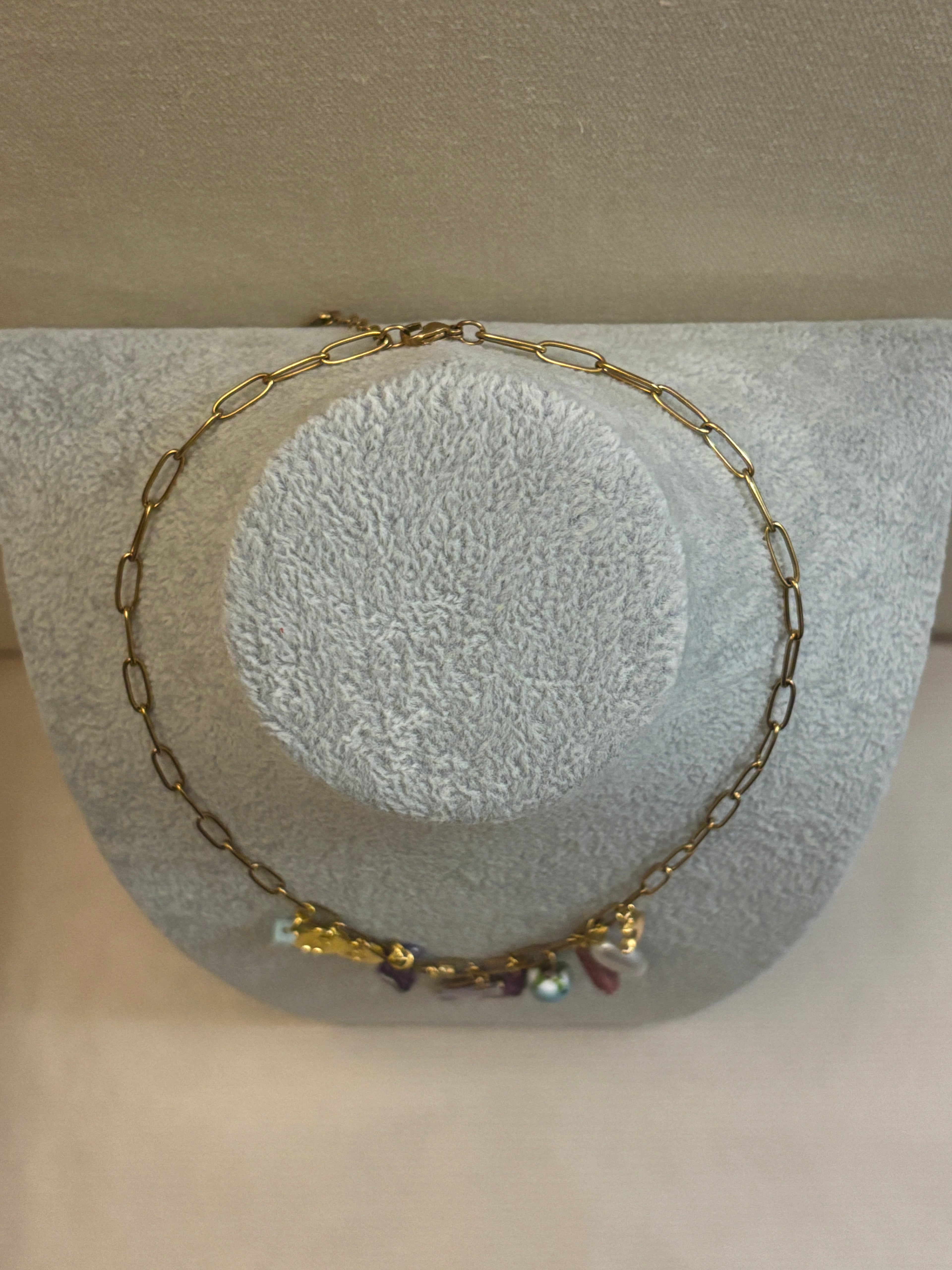 Gold chain bracelet with small beads on a textured stone surface