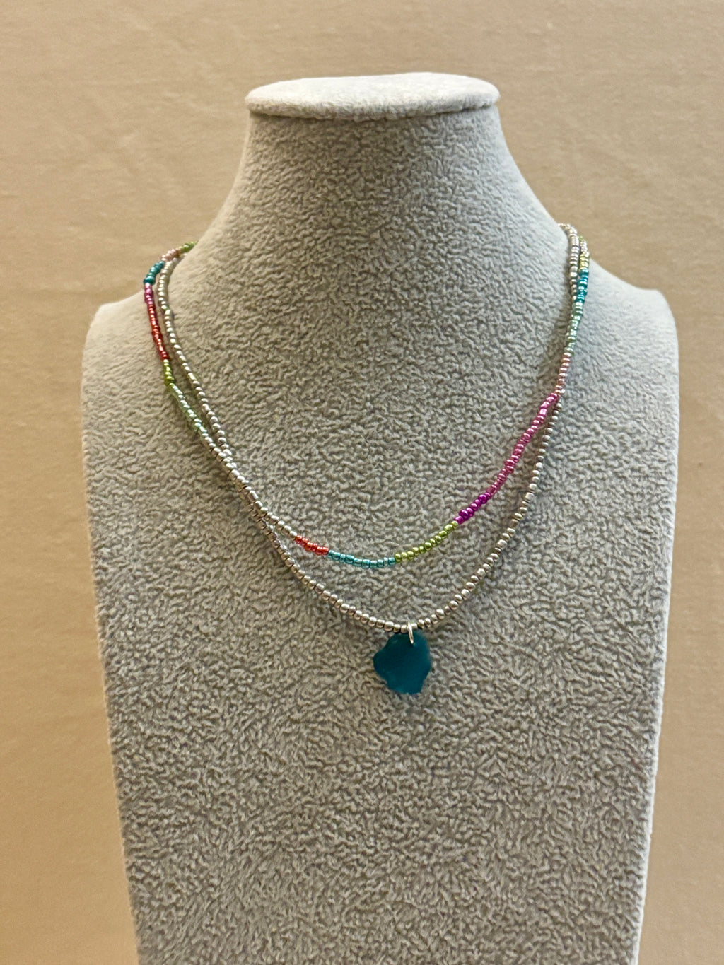 Necklace with a blue pendant on a mannequin bust against a beige background