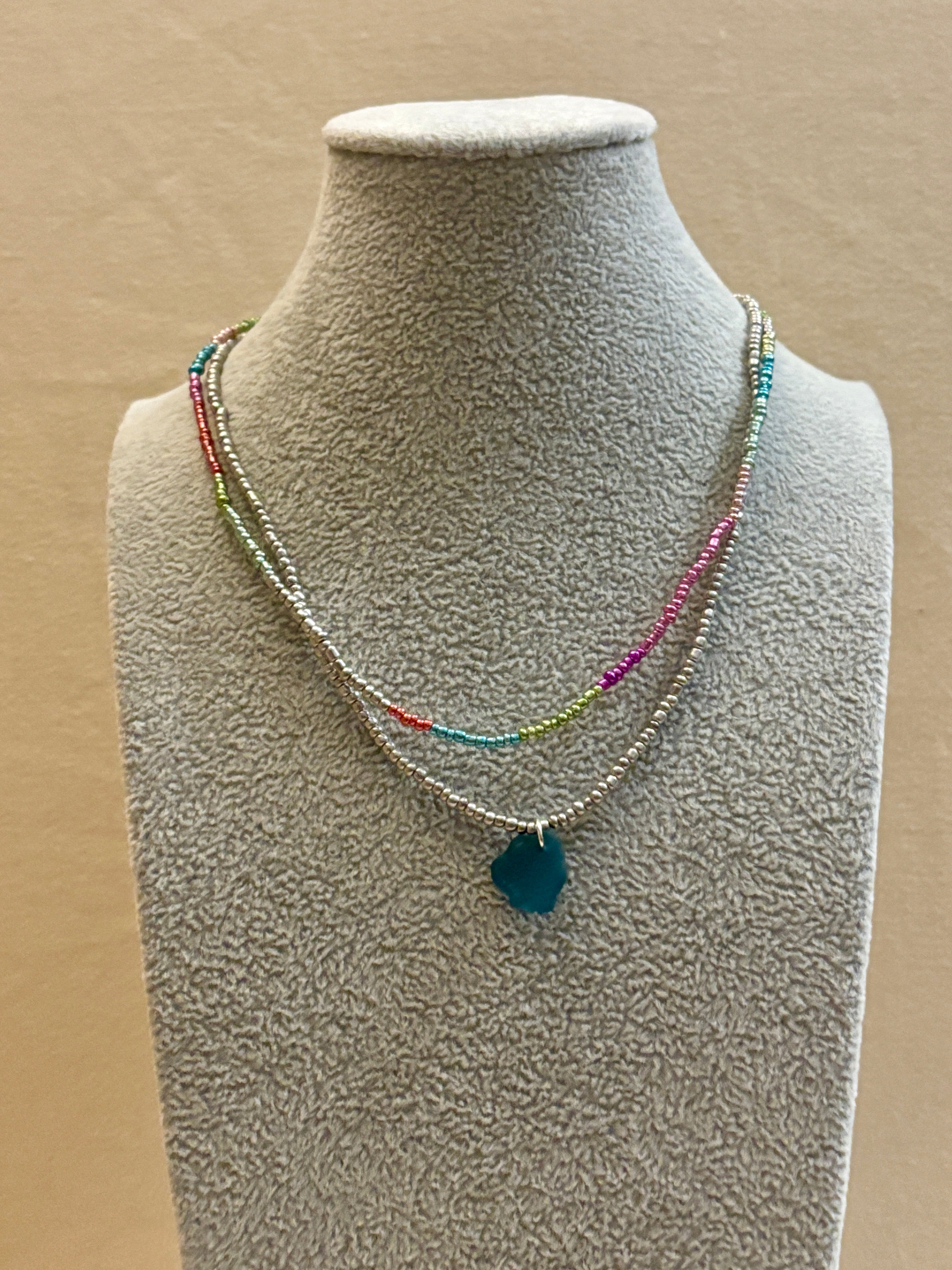 Necklace with a blue pendant on a mannequin bust against a beige background