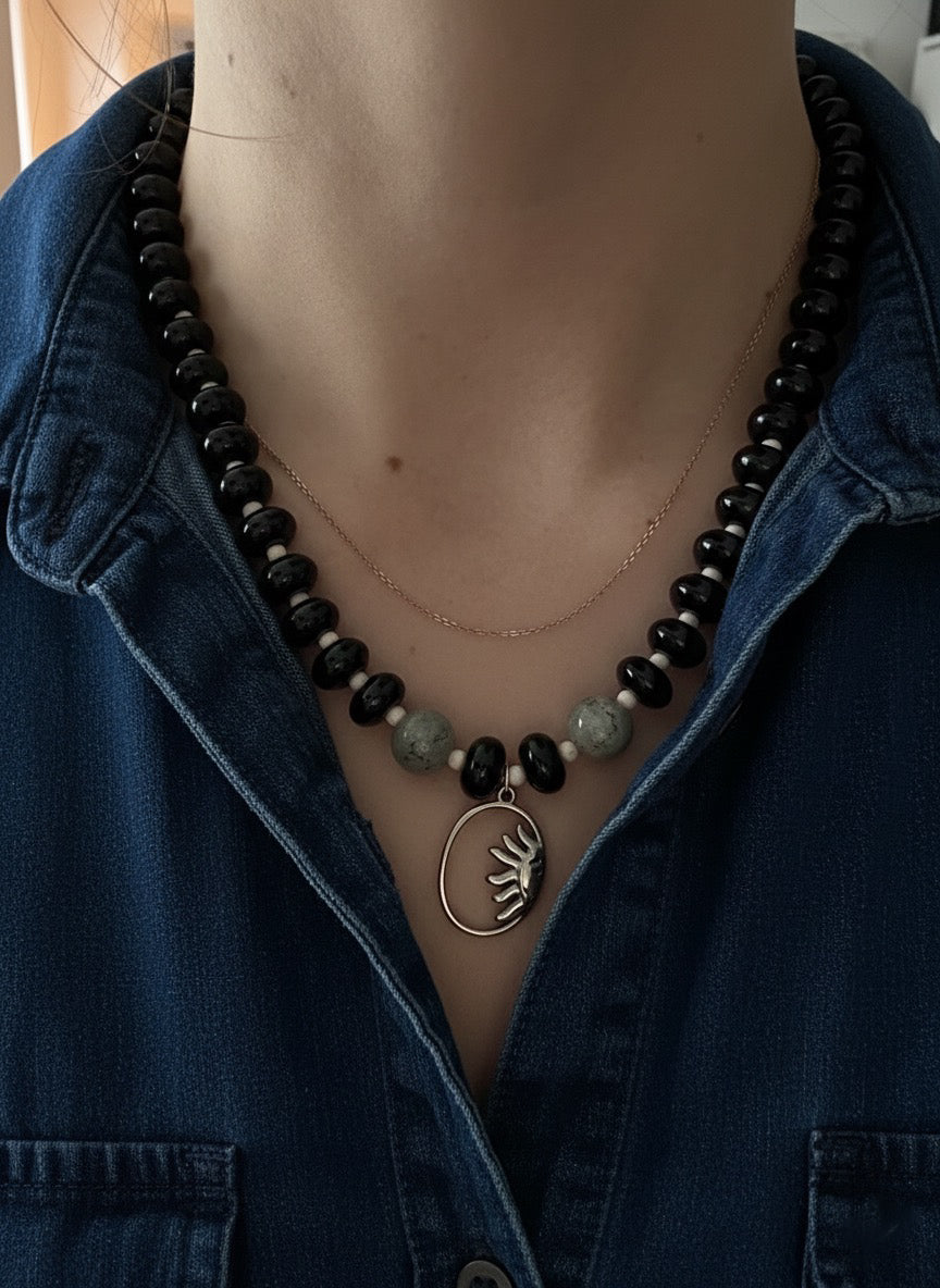 Person wearing an onyx beaded necklace with a blue denim jacket